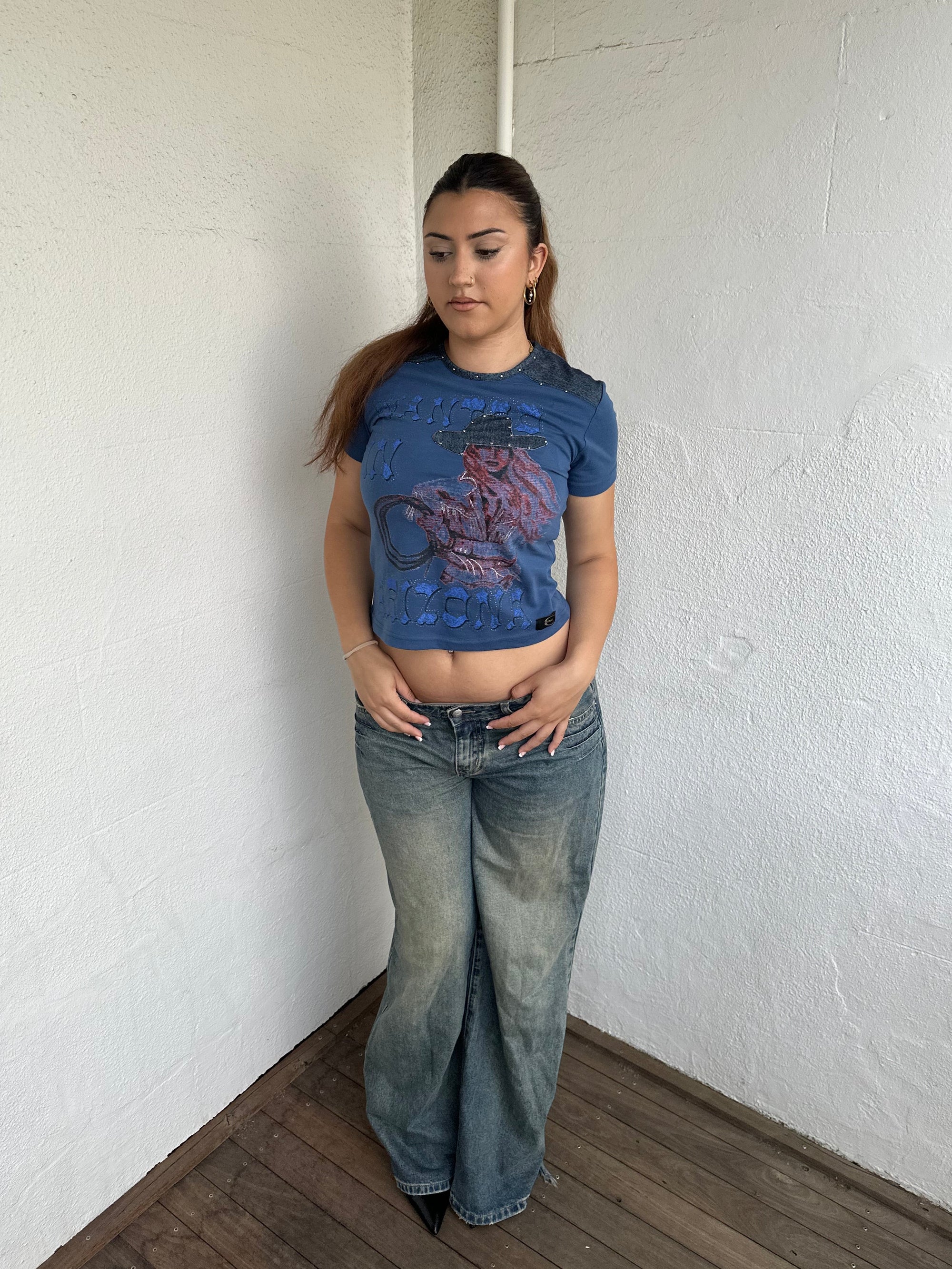 Woman Dressed in Y2K 00s Designer Just Cavalli cowgirl t-shirt featuring a woman cowgirl graphic print with western-style text. 