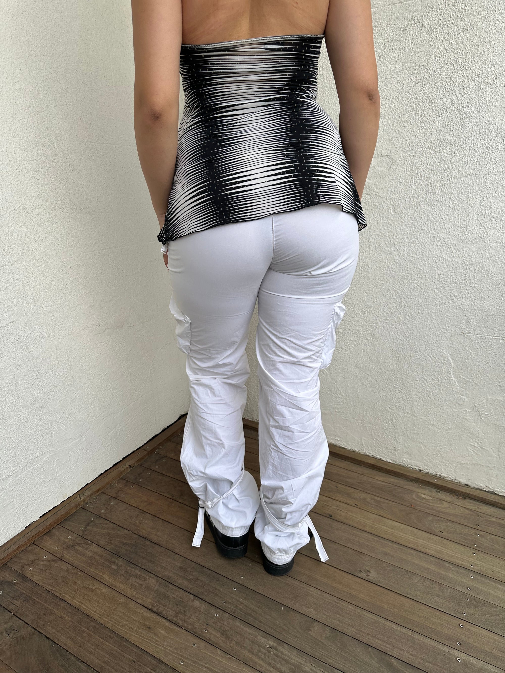 Woman Dressed in Y2K 00s white low-rise cargo pants, classic cargo pocket detailing and strap details.