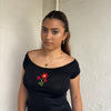 Woman Dressed in Y2K 00s90s flower embroidered wide neck top featuring a red flower embroidery at the centre. 