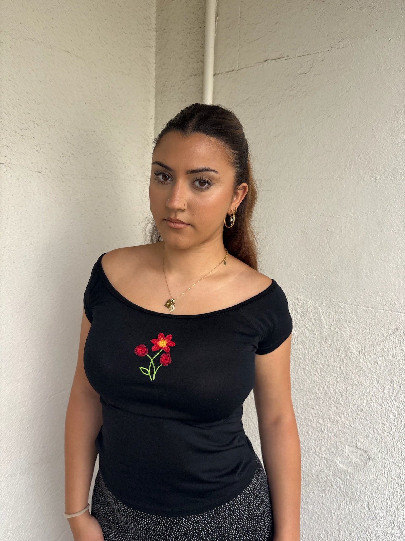 Woman Dressed in Y2K 00s90s flower embroidered wide neck top featuring a red flower embroidery at the centre. 