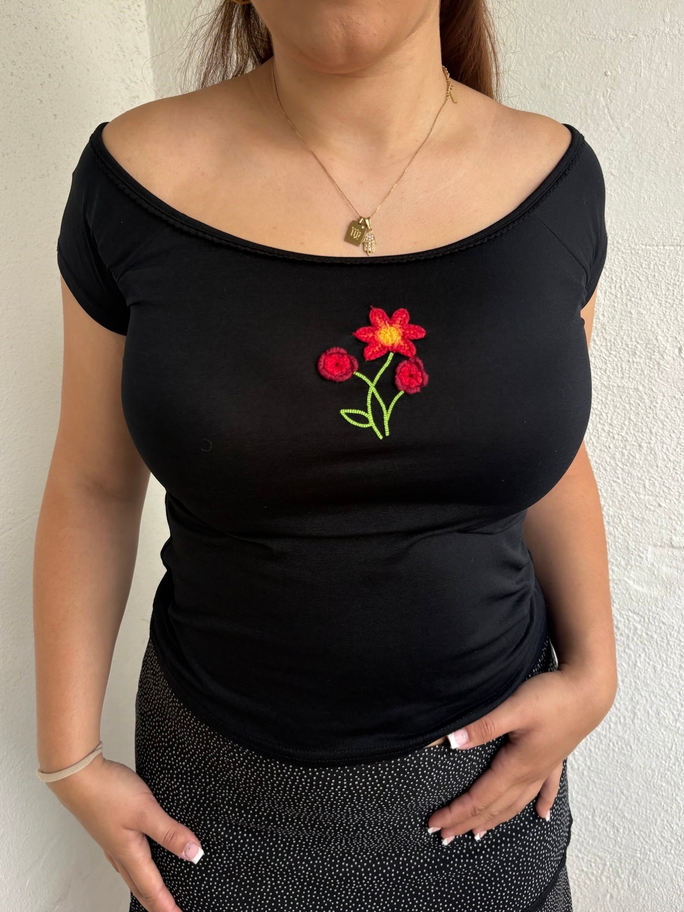 Woman Dressed in Y2K 00s90s flower embroidered wide neck top featuring a red flower embroidery at the centre. 
