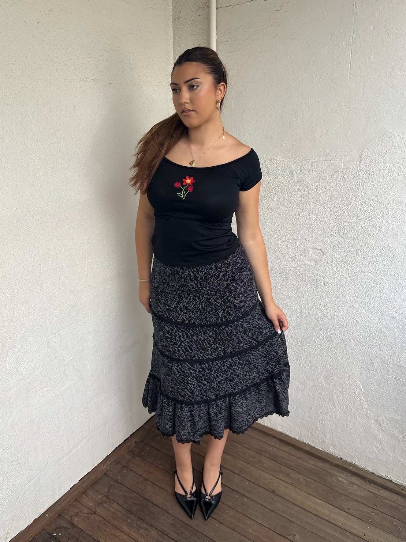 Woman Dressed in Y2K 00s90s flower embroidered wide neck top featuring a red flower embroidery at the centre. 
