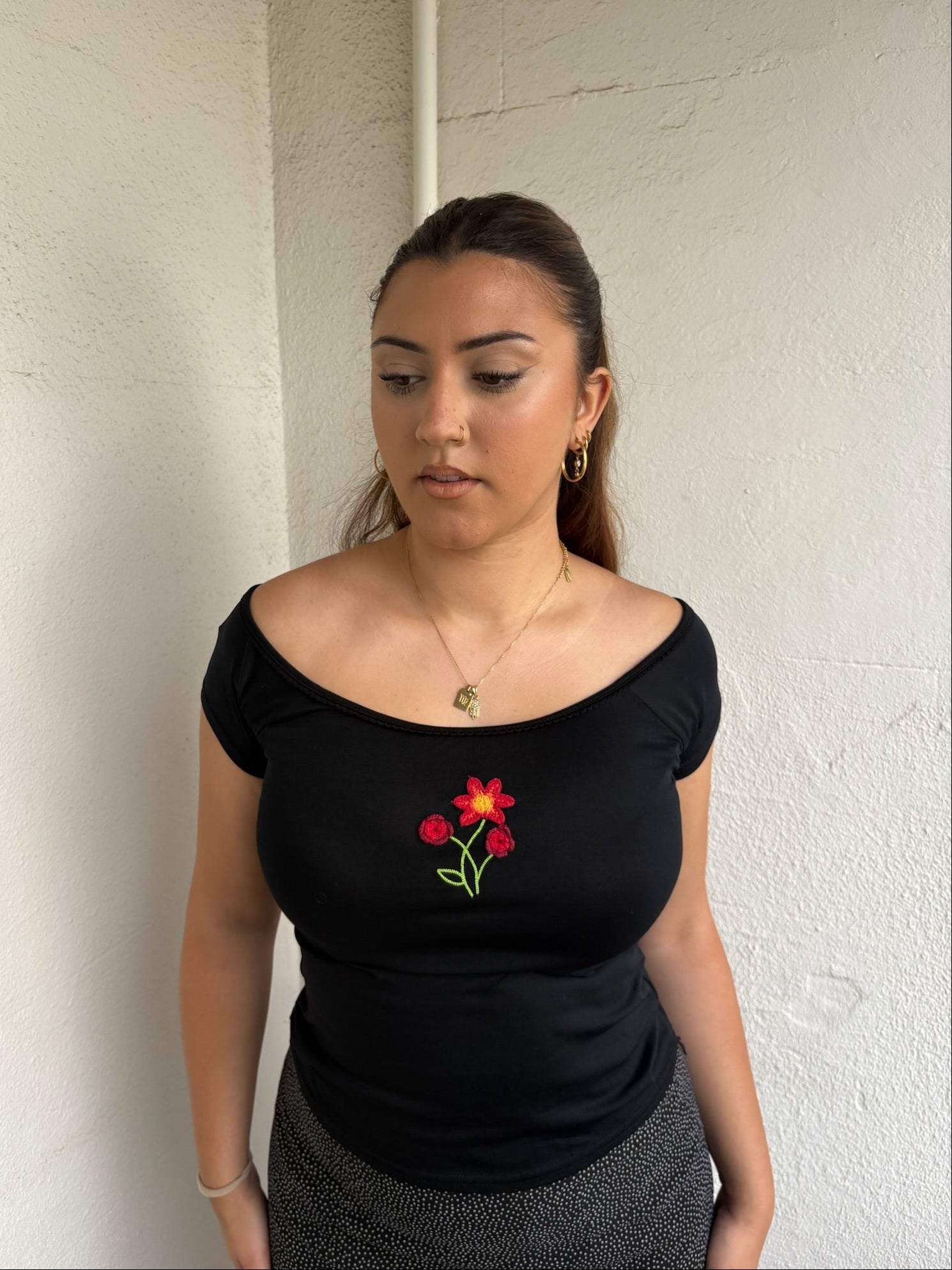 Woman Dressed in Y2K 00s90s flower embroidered wide neck top featuring a red flower embroidery at the centre.