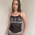 Woman wearing a Y2K 00s Black with white floral embroidery mesh cami top 
