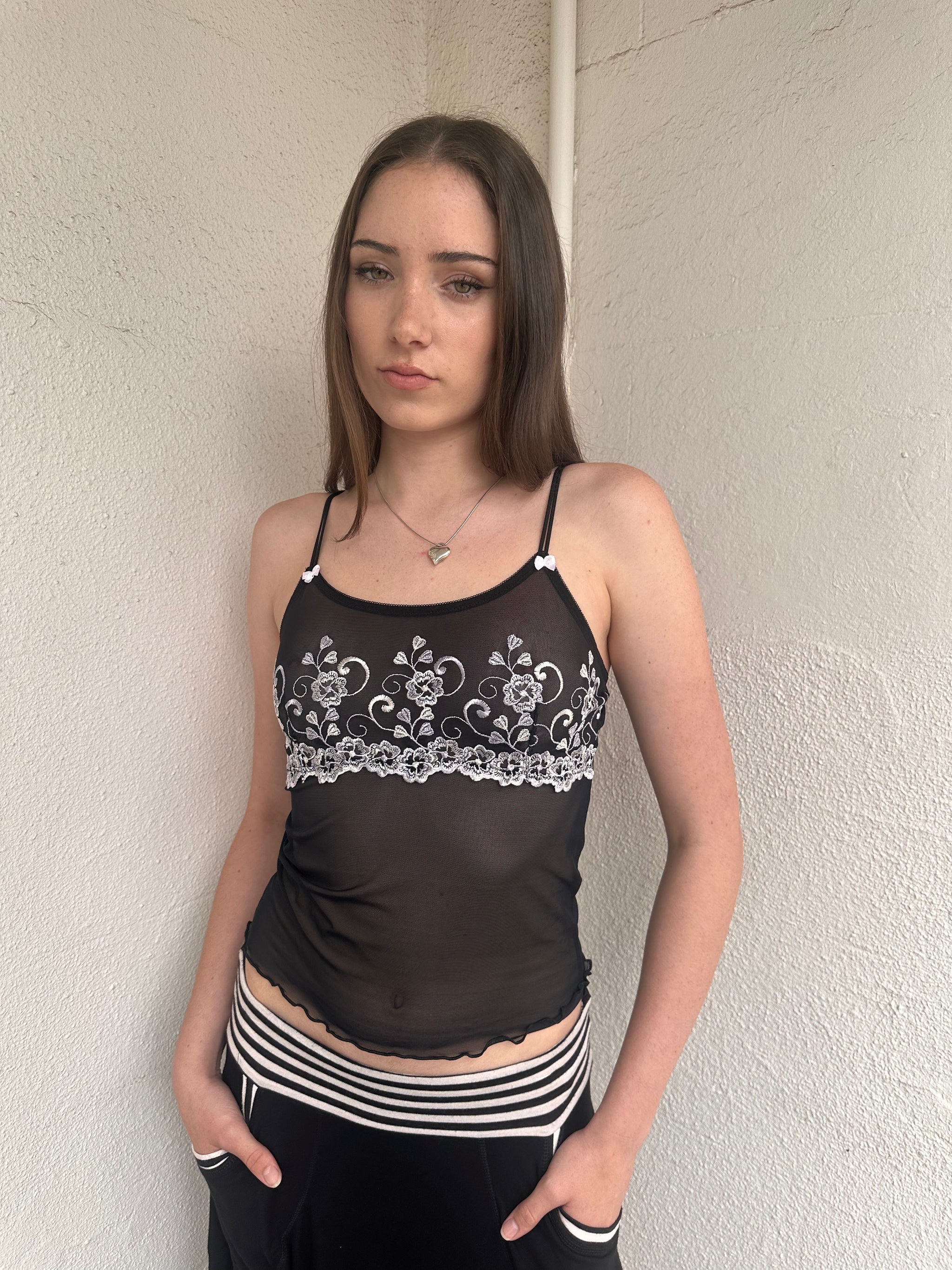 Woman wearing a Y2K 00s Black with white floral embroidery mesh cami top 