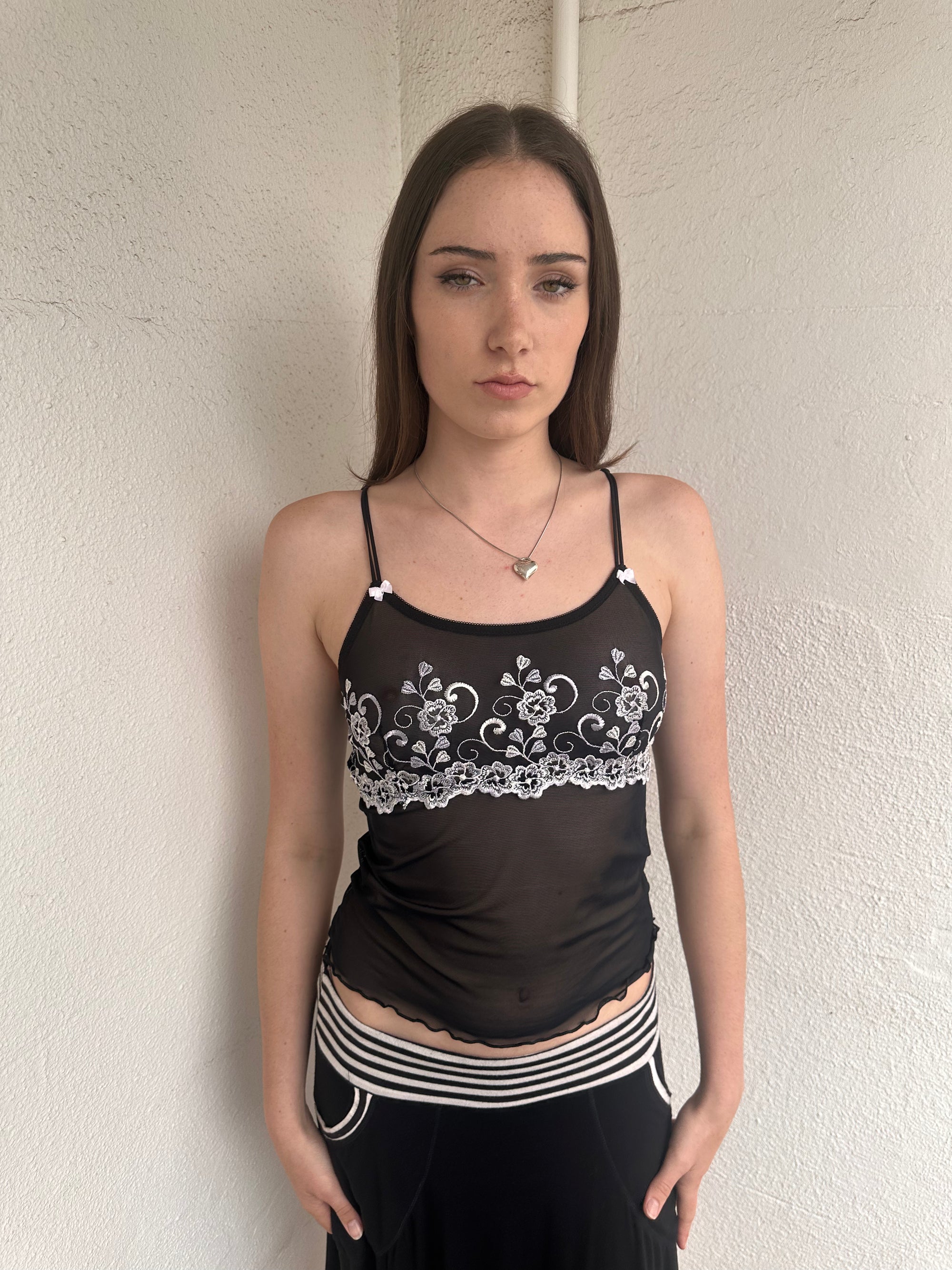 Woman wearing a Y2K 00s Black with white floral embroidery mesh cami top 