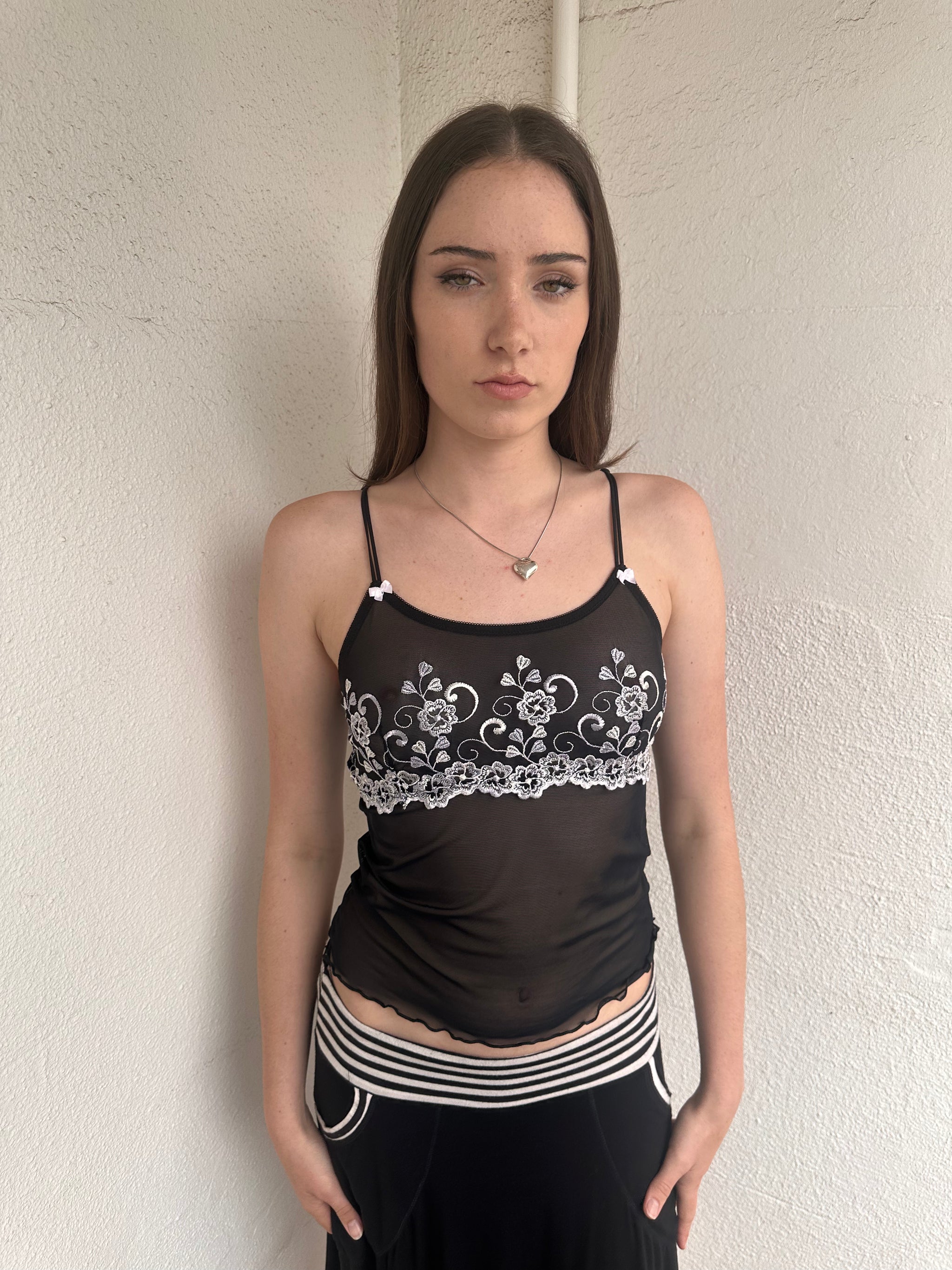 Woman wearing a Y2K 00s Black with white floral embroidery mesh cami top 