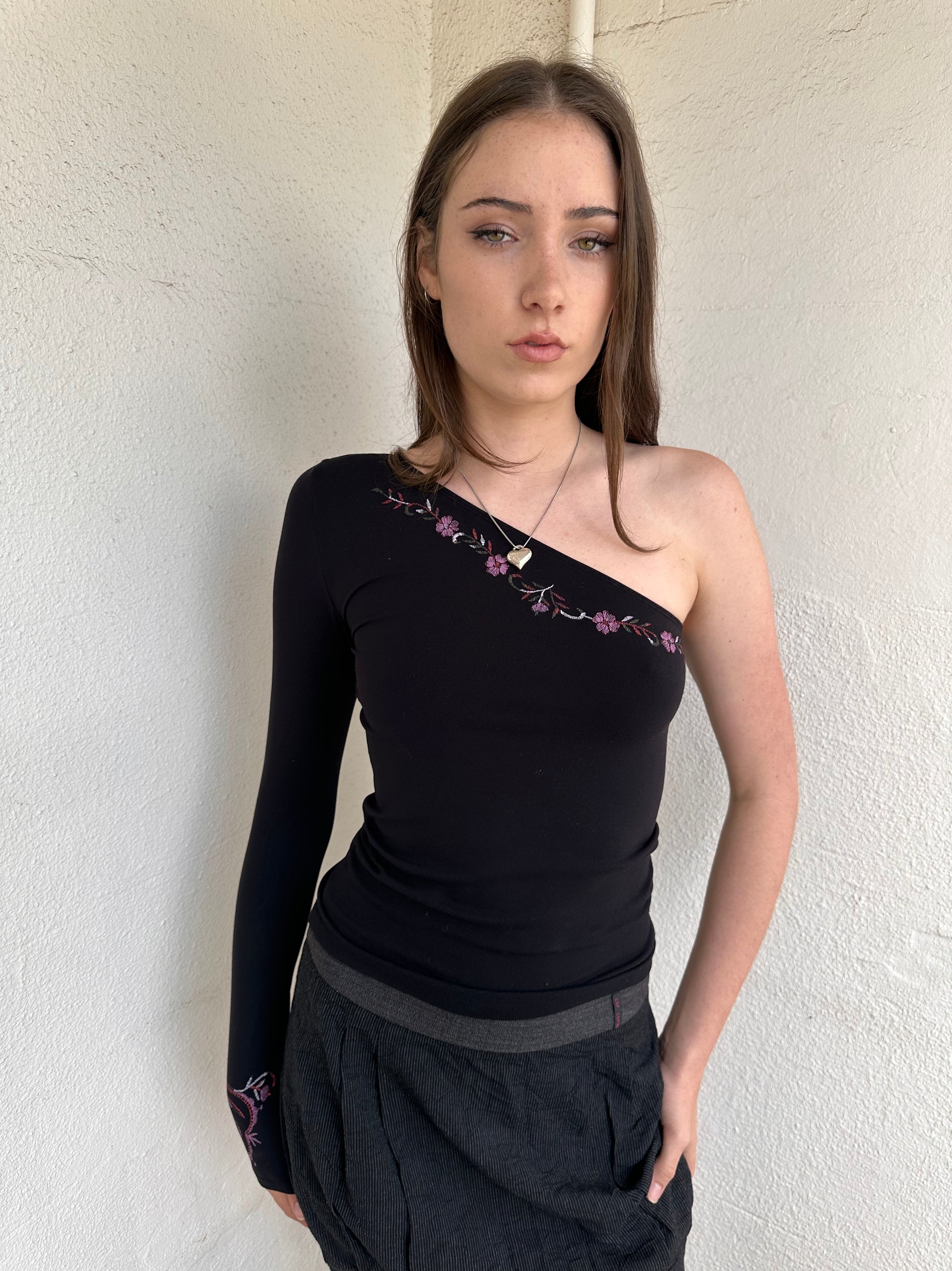 Woman wearing a Y2K 00s black one shoulder one sleeve with purple floral print 