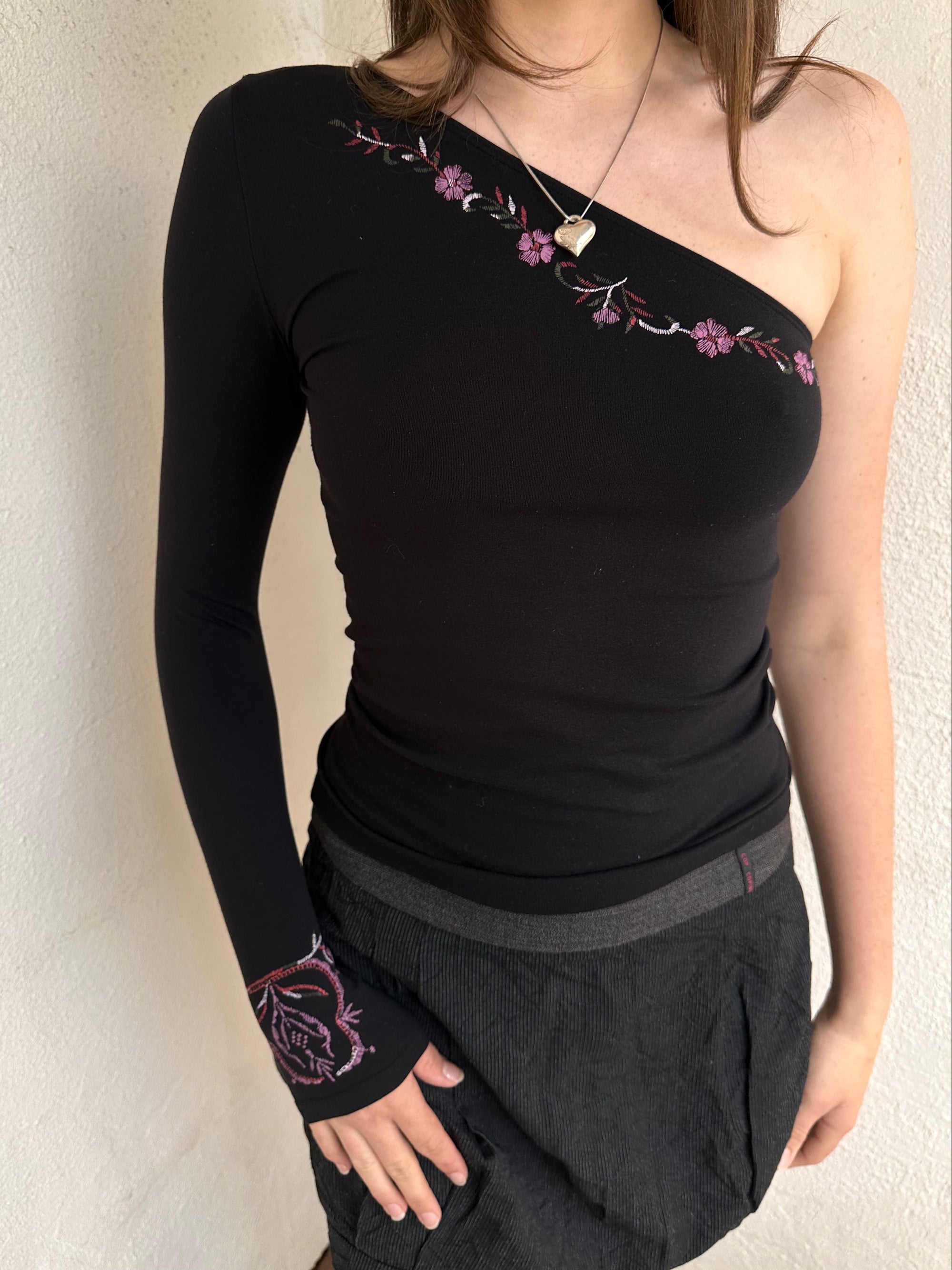 Woman wearing a Y2K 00s black one shoulder one sleeve with purple floral print 