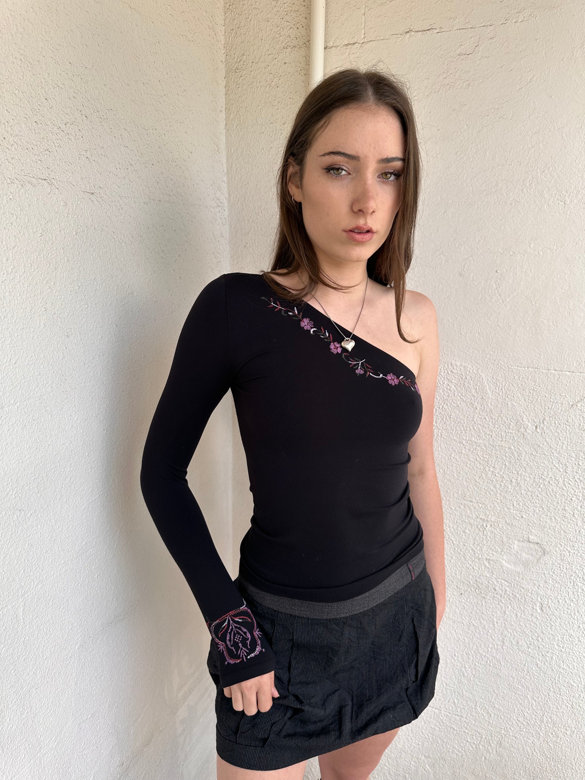 Woman wearing a Y2K 00s black one shoulder one sleeve with purple floral print 