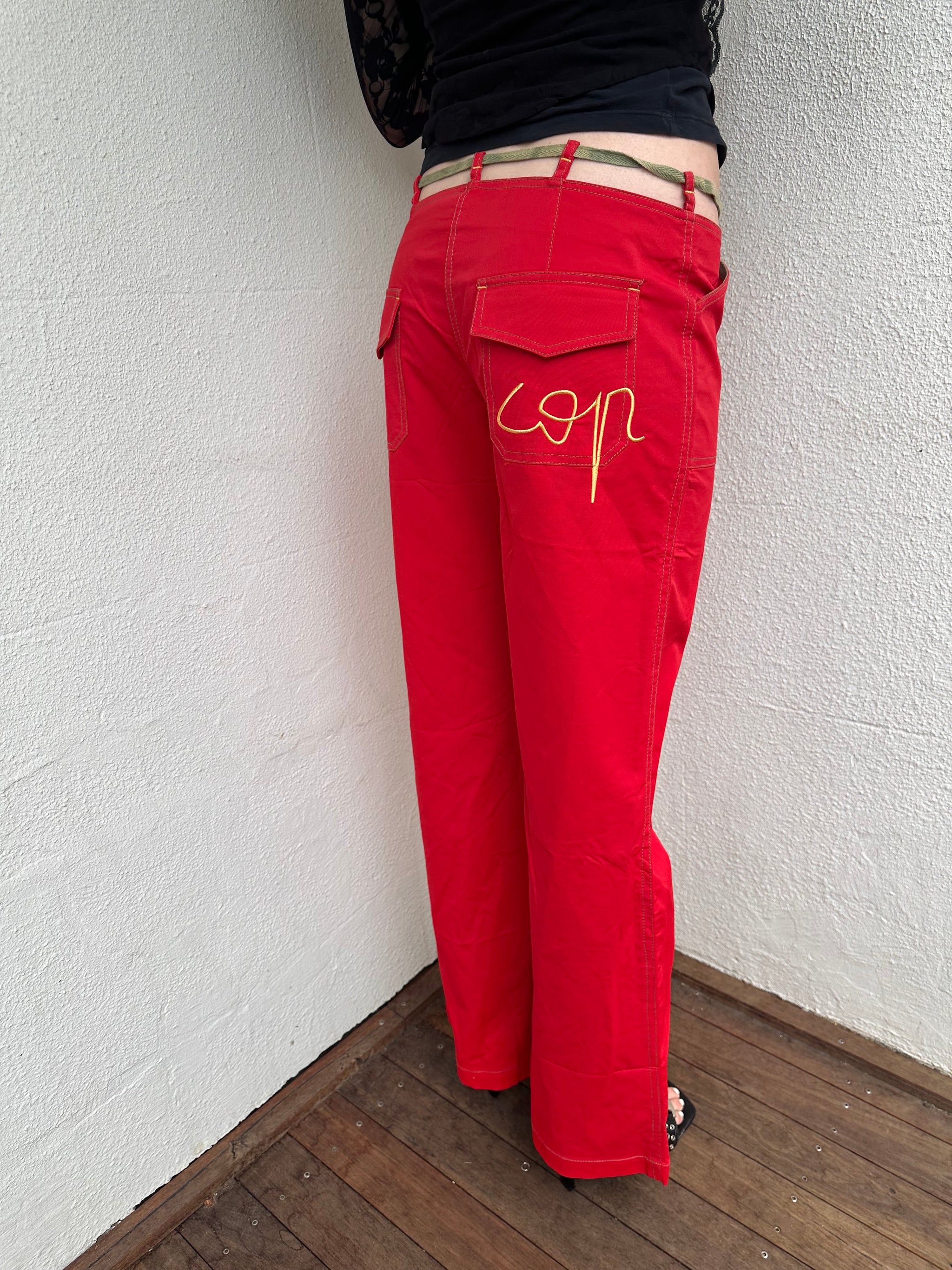 Woman wearing a Y2K 00s Cop copine red straight leg and low waited pants with cut out waistband and yellow embroidery 