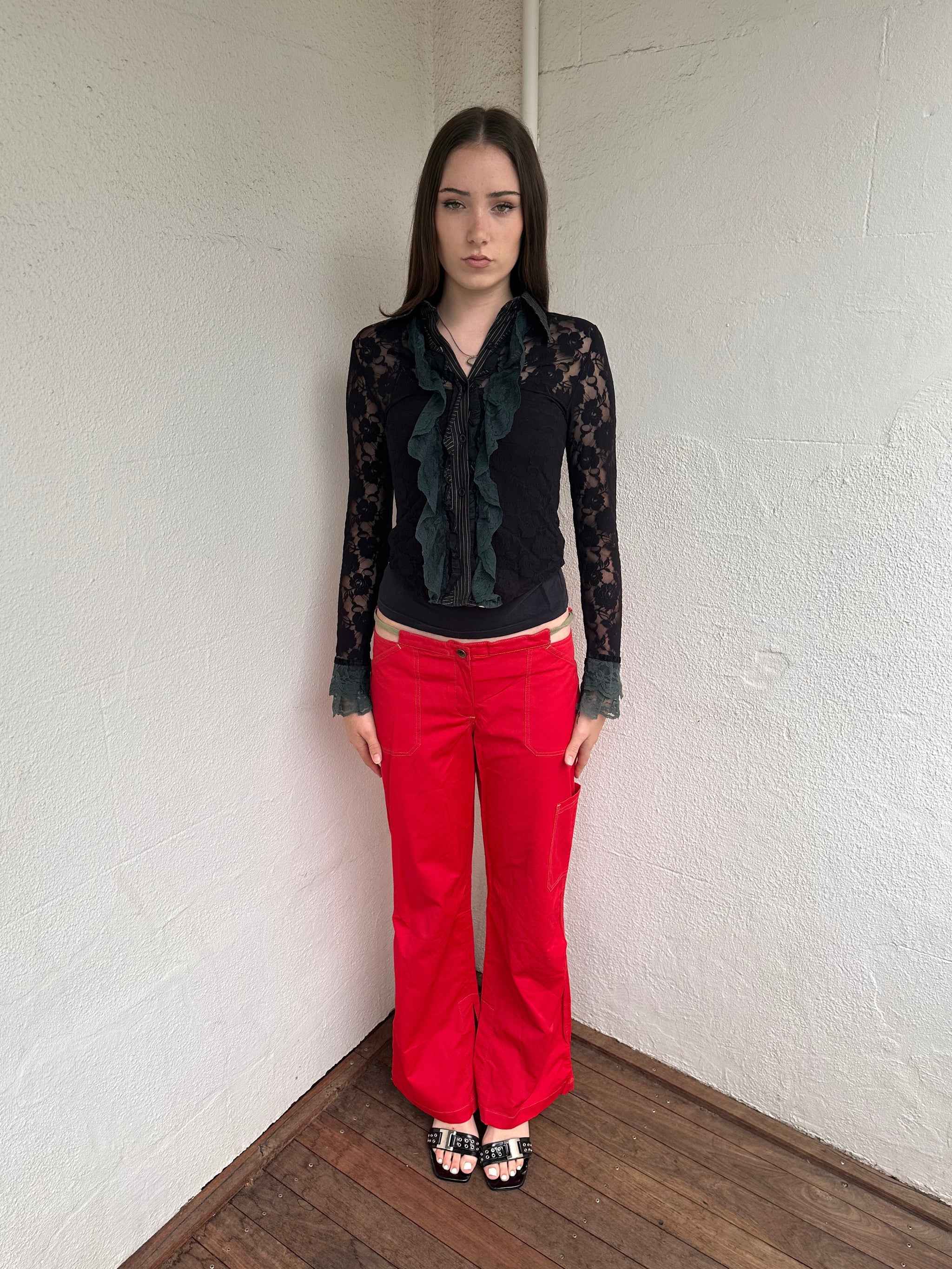 Woman wearing a Y2K 00s Cop copine red straight leg and low waited pants with cut out waistband and yellow embroidery 