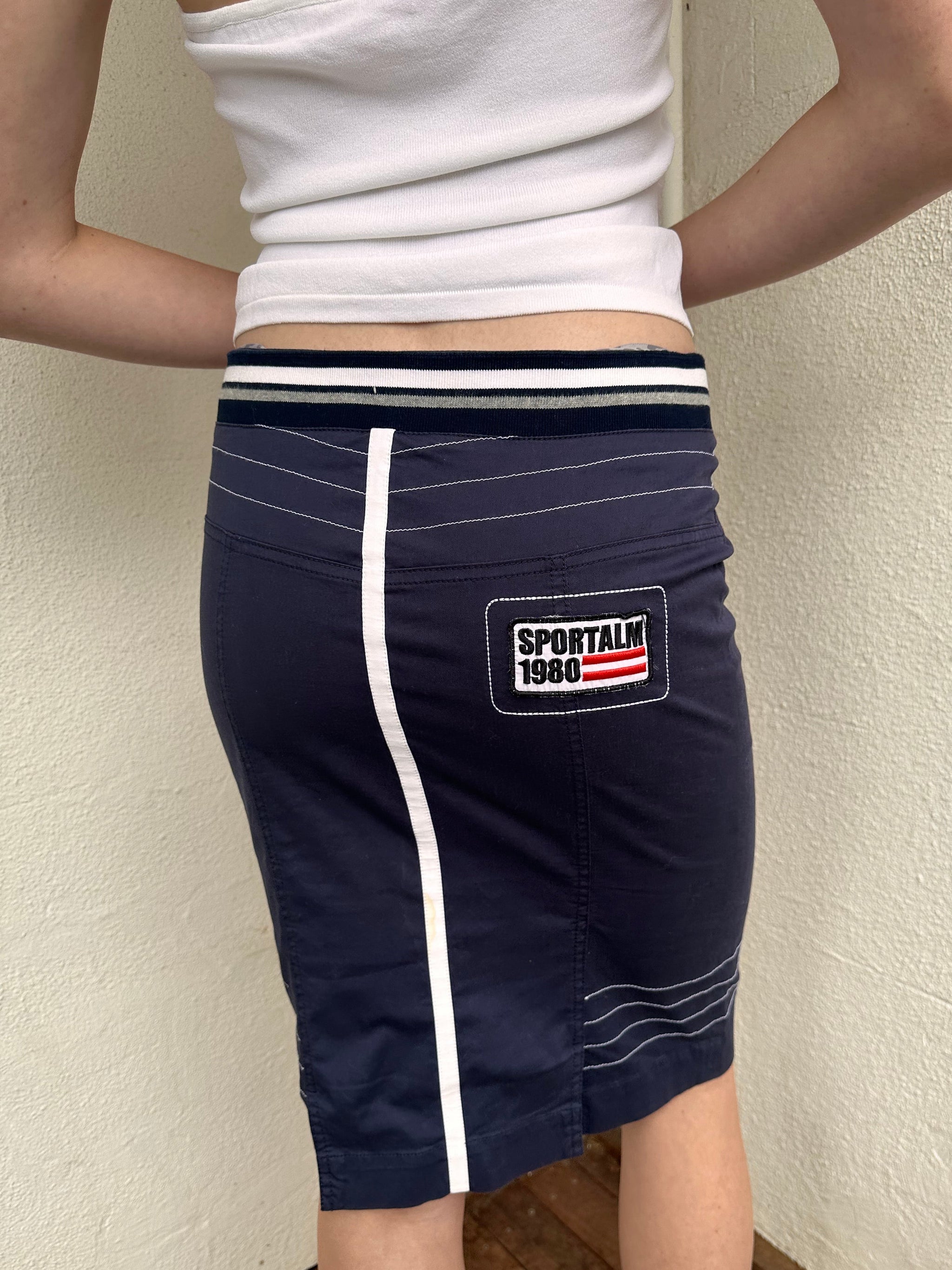 Woman wearing a Y2K 00s sportalm navy and white sporty midi skirt logo patch
