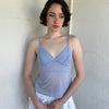 Woman Dressed in Y2K Baby blue lace cami top featuring a soft dusky blue tone with a lace bust and sheer mesh body. 