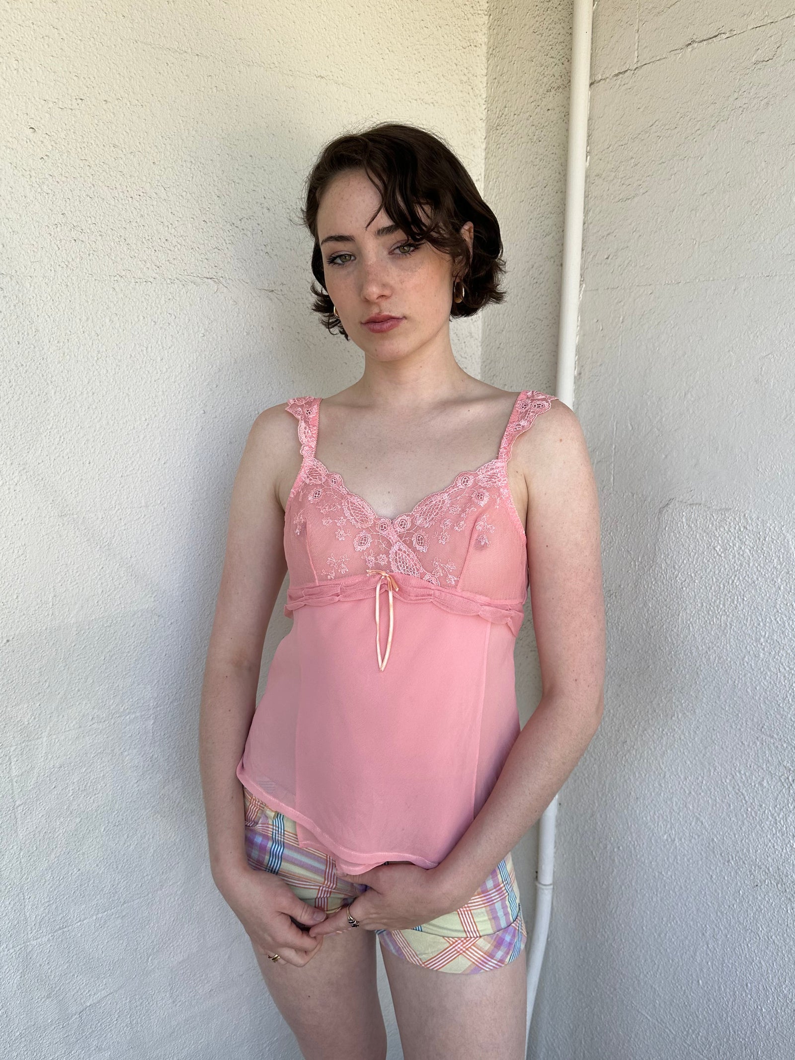 Woman Dressed in Y2K Baby pink embroidered mesh cami top featuring a soft peachy pink tone. 