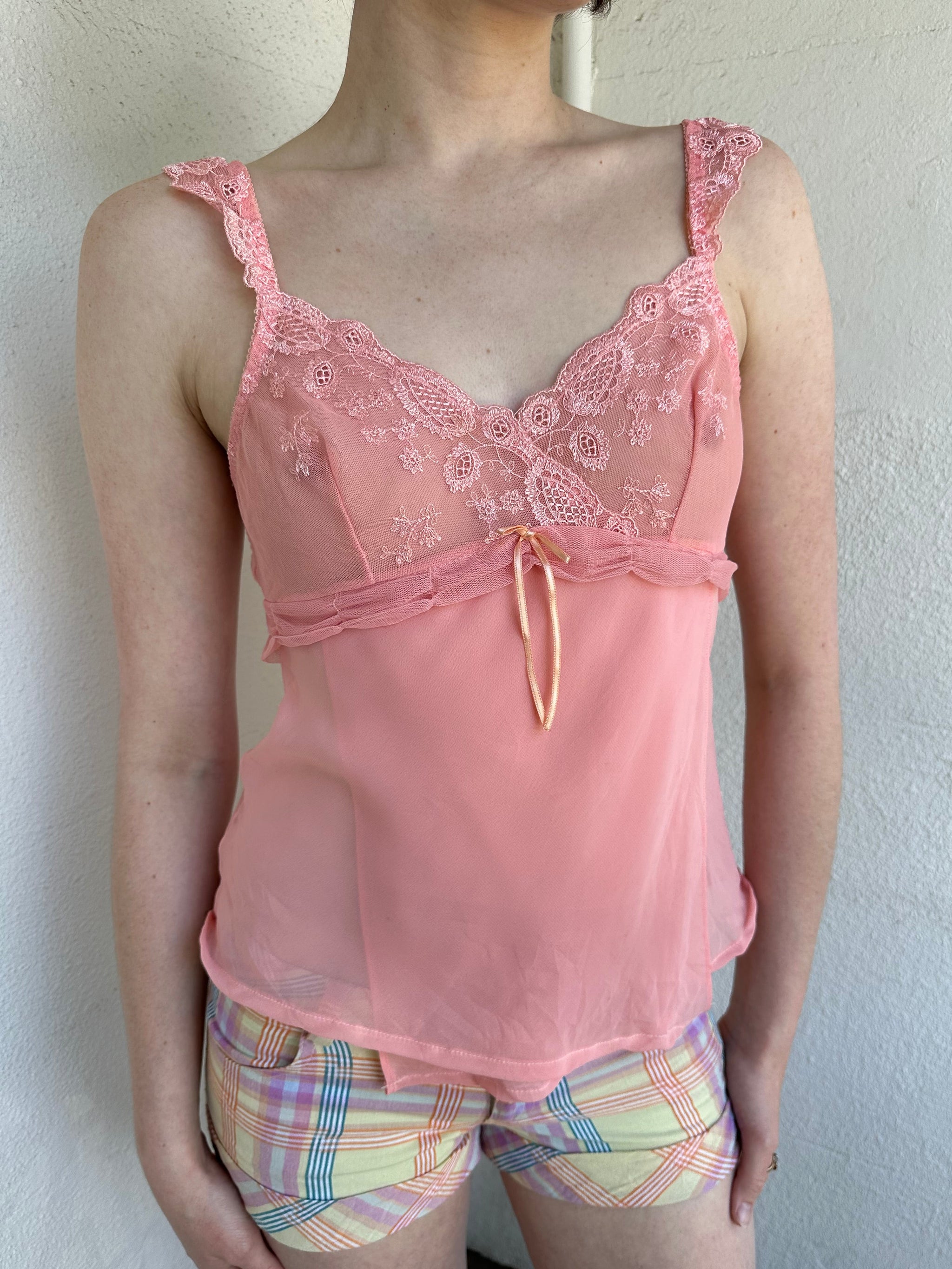 Woman Dressed in Y2K Baby pink embroidered mesh cami top featuring a soft peachy pink tone. 