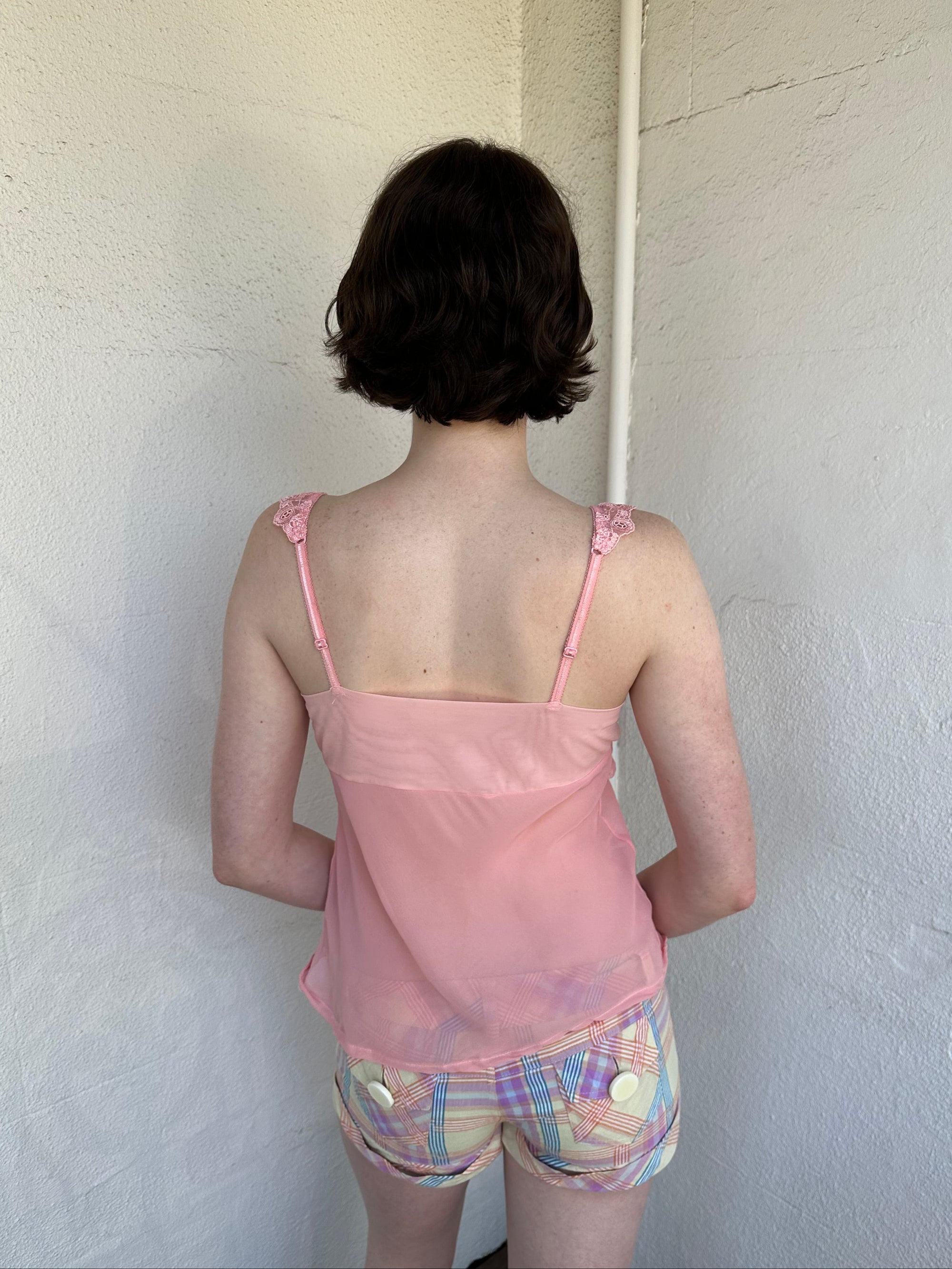 Woman Dressed in Y2K Baby pink embroidered mesh cami top featuring a soft peachy pink tone. 