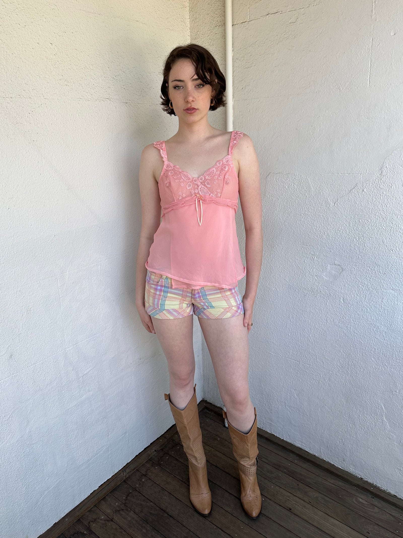 Woman Dressed in Y2K Baby pink embroidered mesh cami top featuring a soft peachy pink tone. 