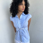 Woman wearing a Y2K 00s Baby blue gingham shirt with, featuring delicate ruffles down the front