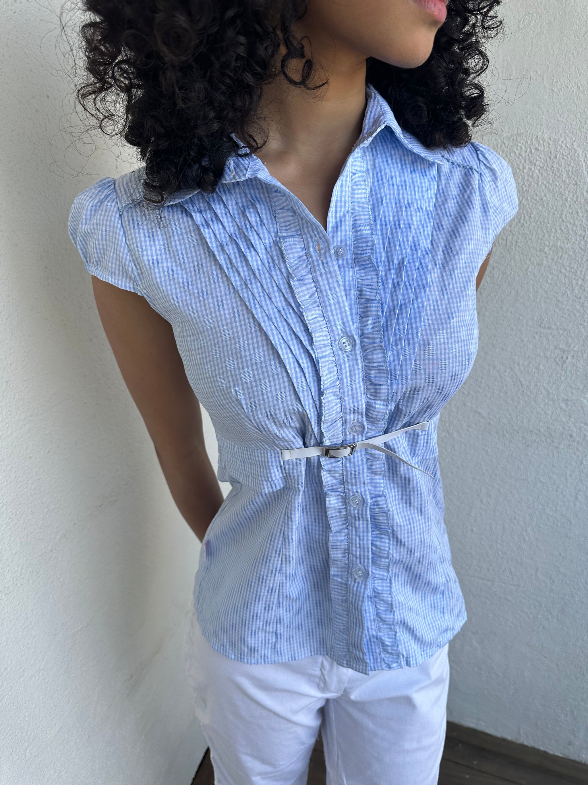 Woman wearing a Y2K 00s Baby blue gingham shirt with, featuring delicate ruffles down the front