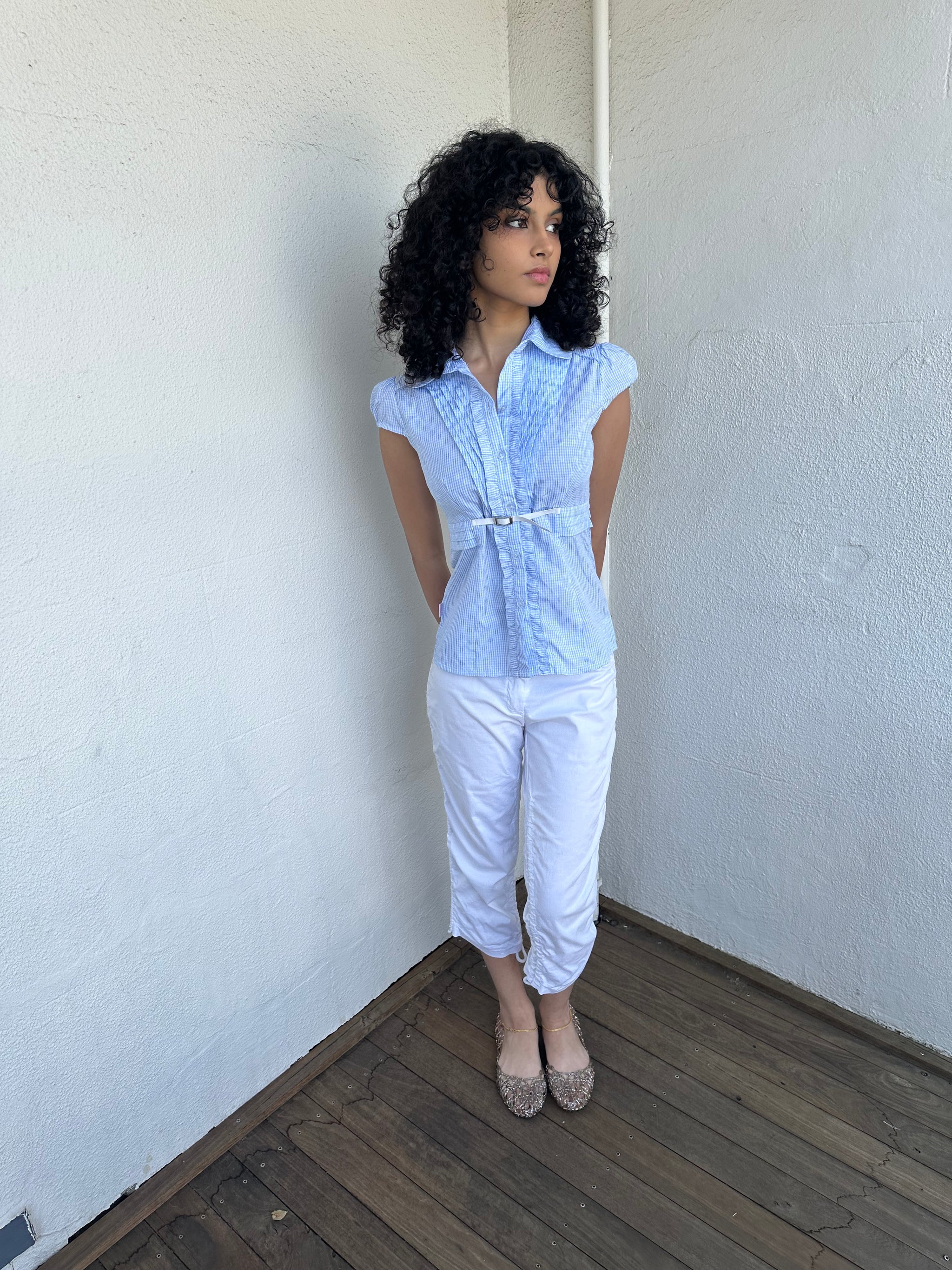 Woman wearing a Y2K 00s Baby blue gingham shirt with, featuring delicate ruffles down the front