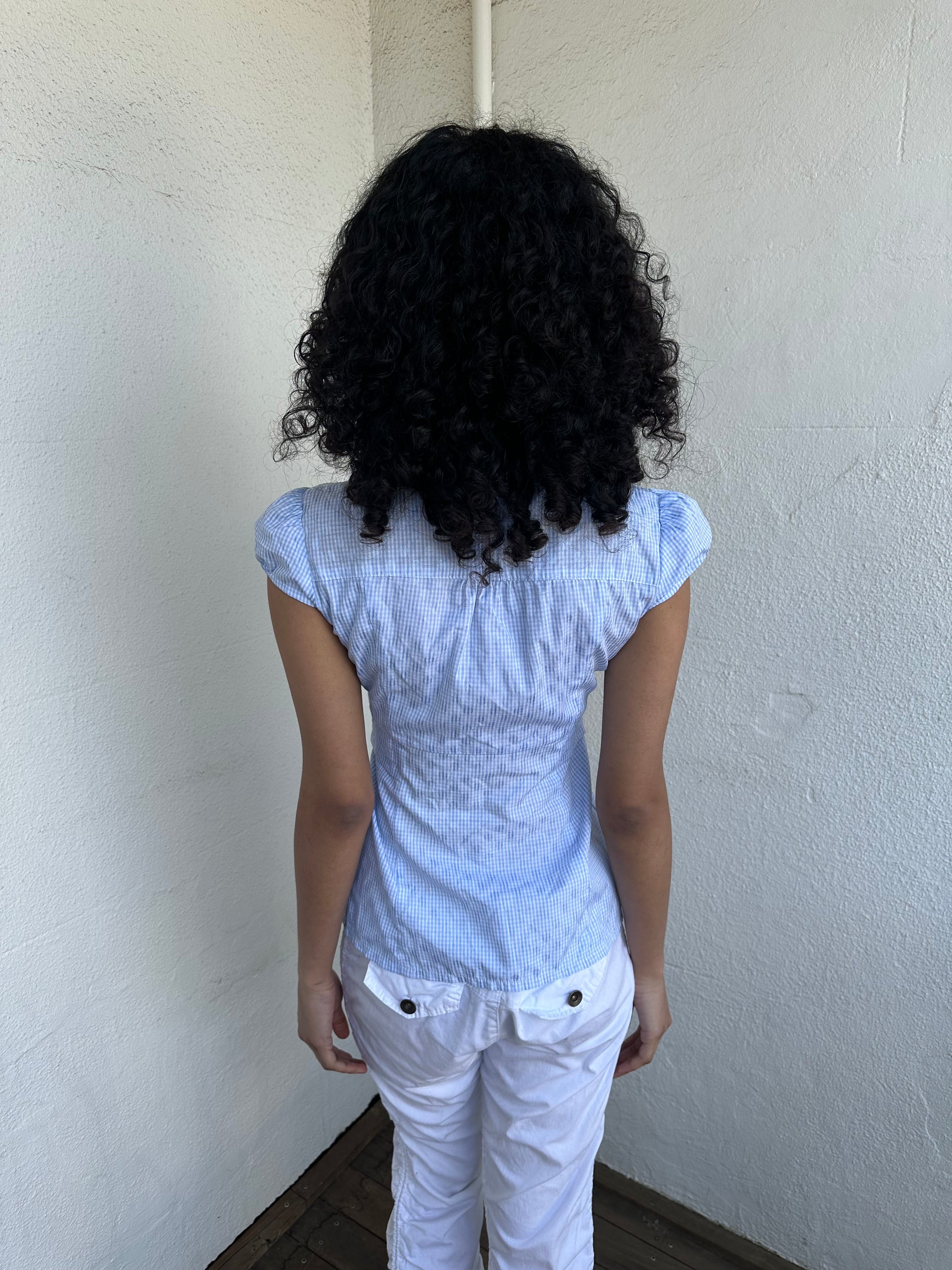 Woman wearing a Y2K 00s Baby blue gingham shirt with, featuring delicate ruffles down the front