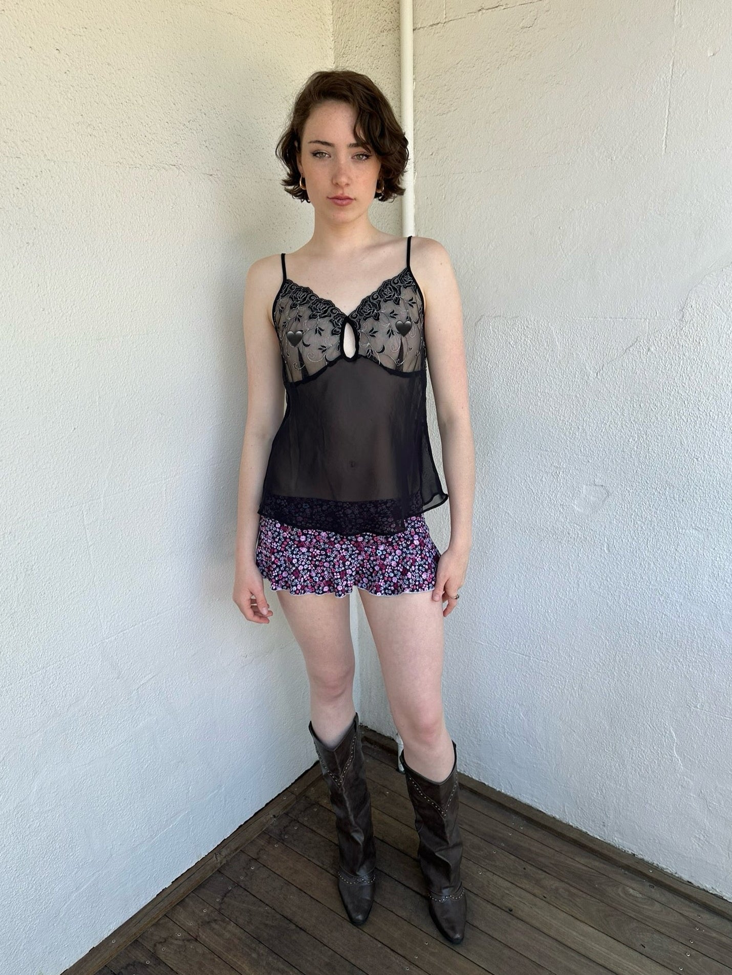 Woman Dressed in Y2K Black embroidered mesh cami top featuring a sheer bust with black and silver floral embroidery. 