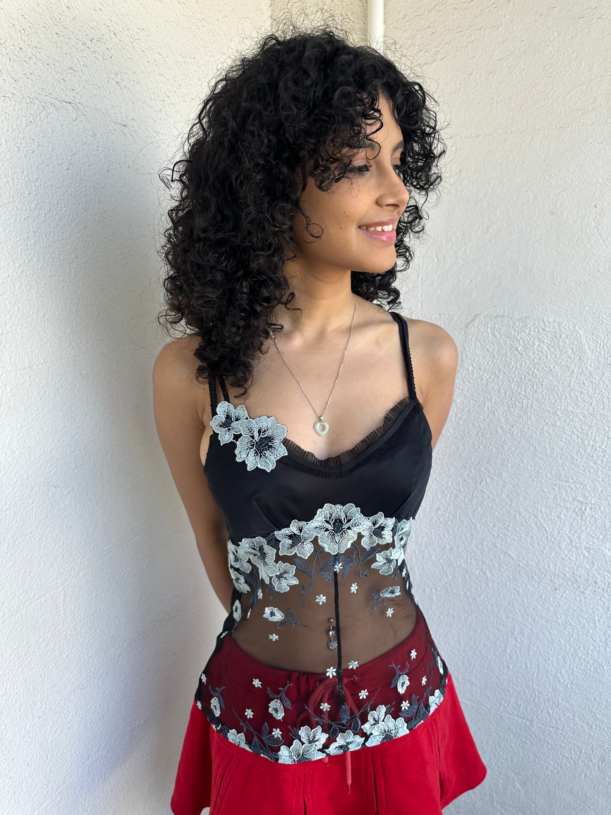 Woman wearing a Y2K 00s Black with white floral embroidery mesh cami top. Light blue floral embroidery featured. 