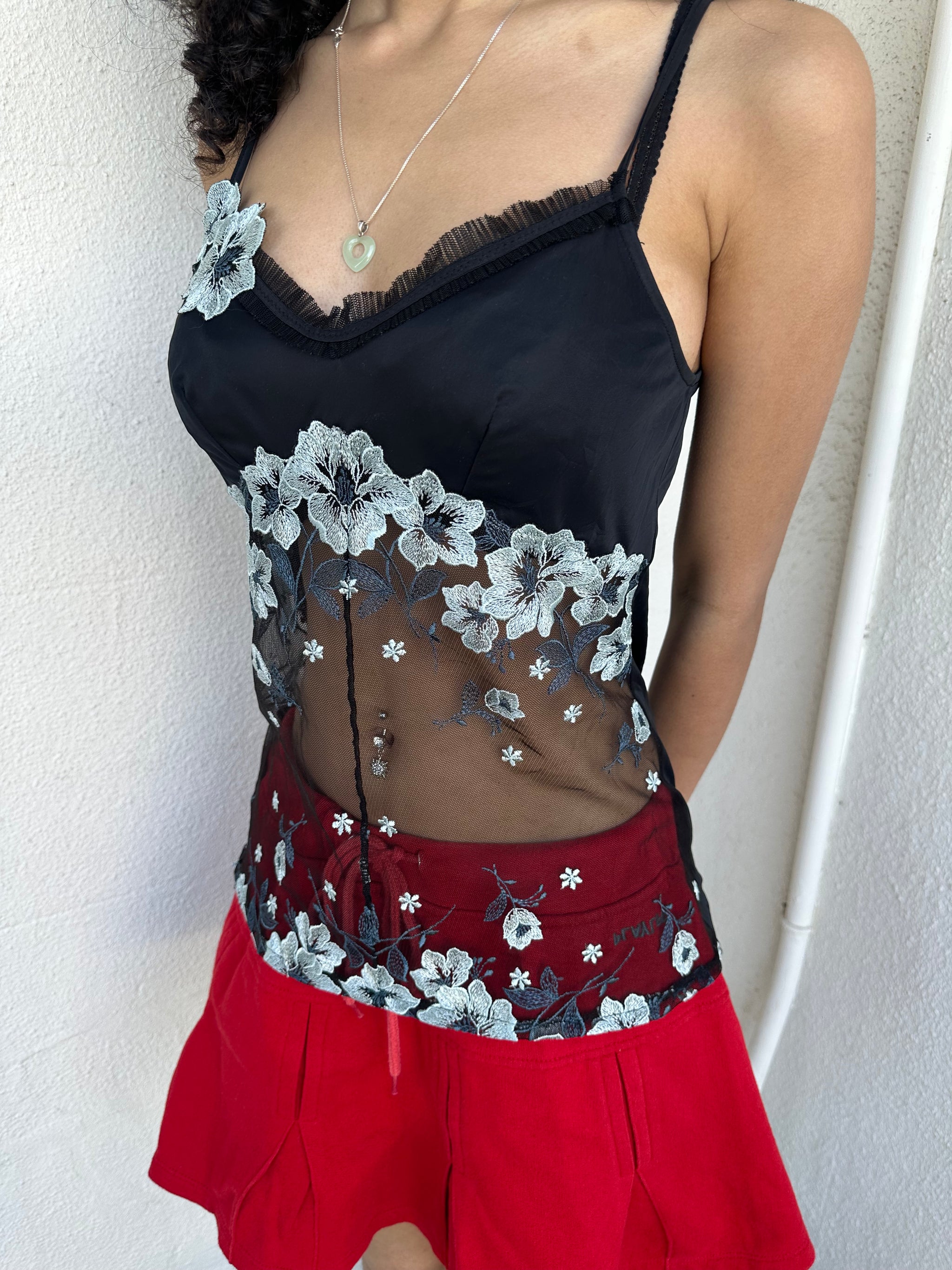 Woman wearing a Y2K 00s Black with white floral embroidery mesh cami top. Light blue floral embroidery featured 
