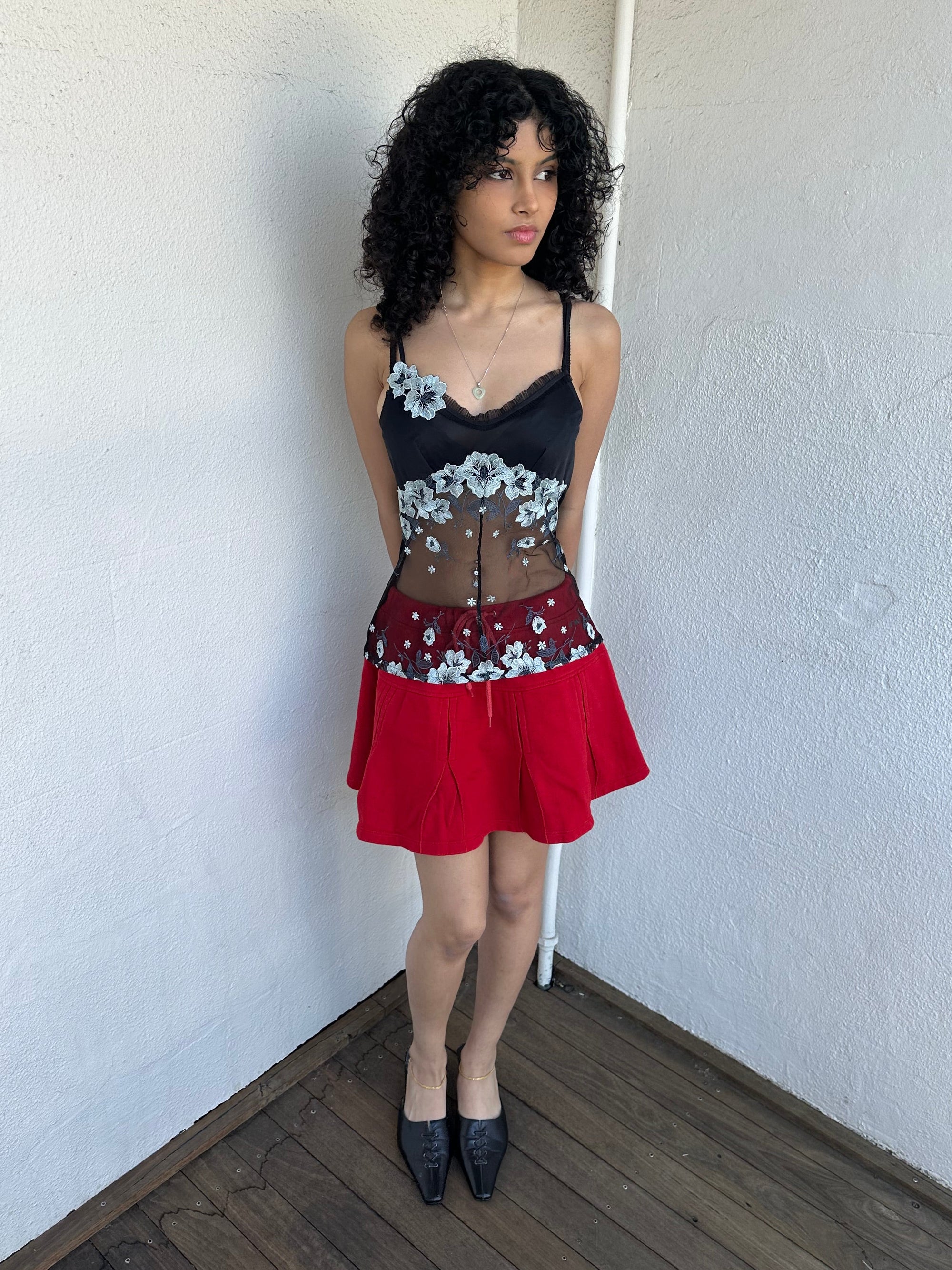 Woman wearing a Y2K 00s Black with white floral embroidery mesh cami top. Light blue floral embroidery featured 