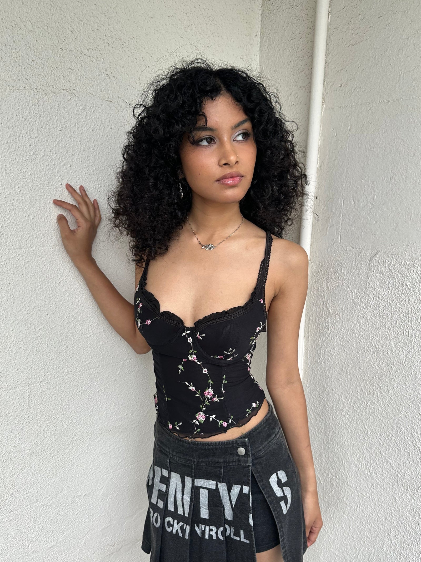 Woman Dressed in Y2K 00s Black floral embroidered Y2K corset with a black base and pink floral embroidery throughout. 