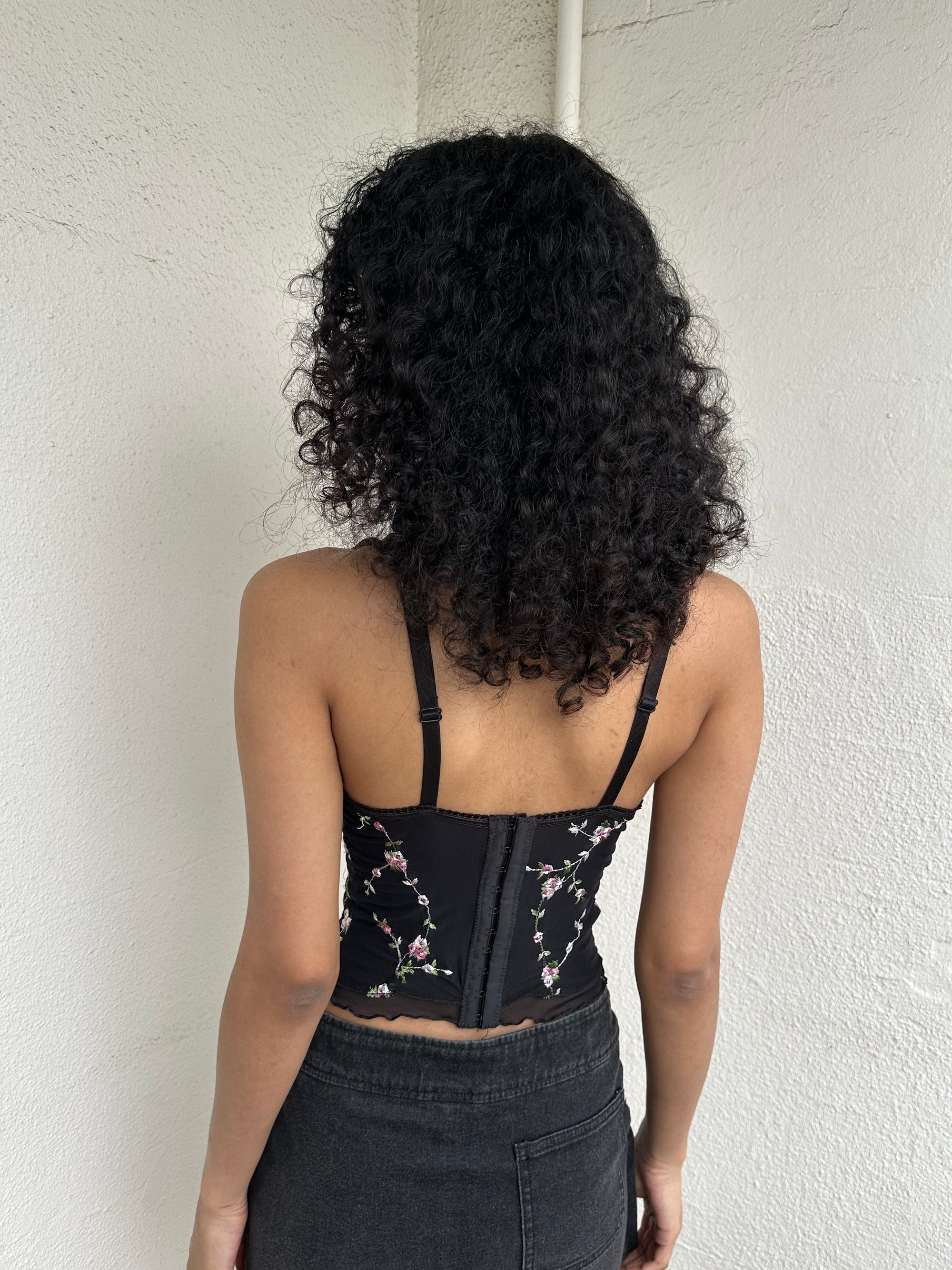 Woman Dressed in Y2K 00s Black floral embroidered Y2K corset with a black base and pink floral embroidery throughout. 