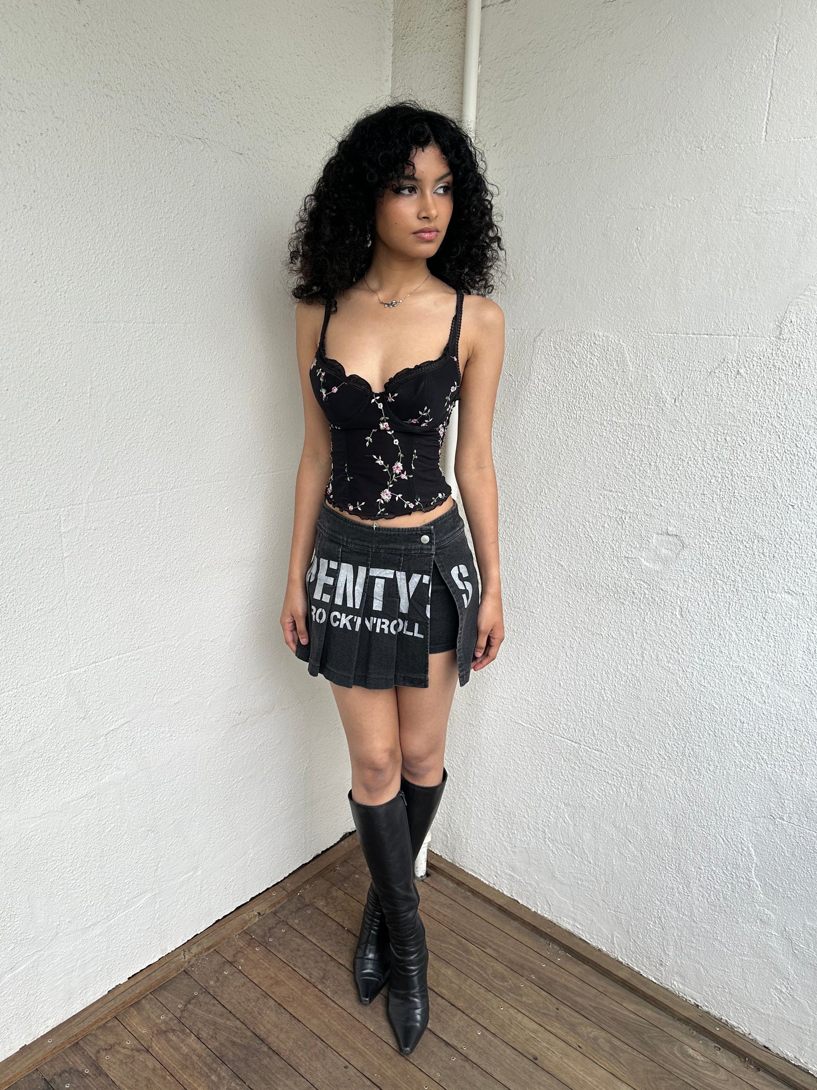 Woman Dressed in Y2K 00s Black floral embroidered Y2K corset with a black base and pink floral embroidery throughout. 