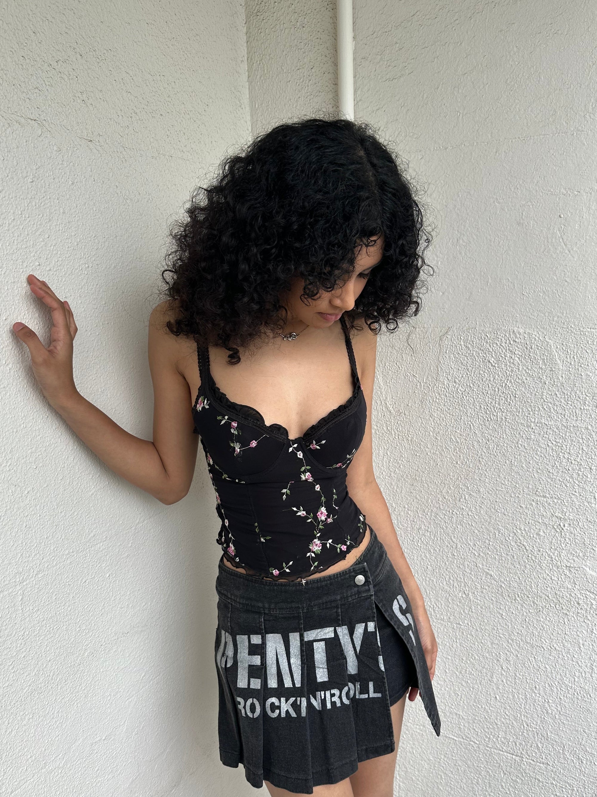 Woman Dressed in Y2K 00s Black floral embroidered Y2K corset with a black base and pink floral embroidery throughout. 