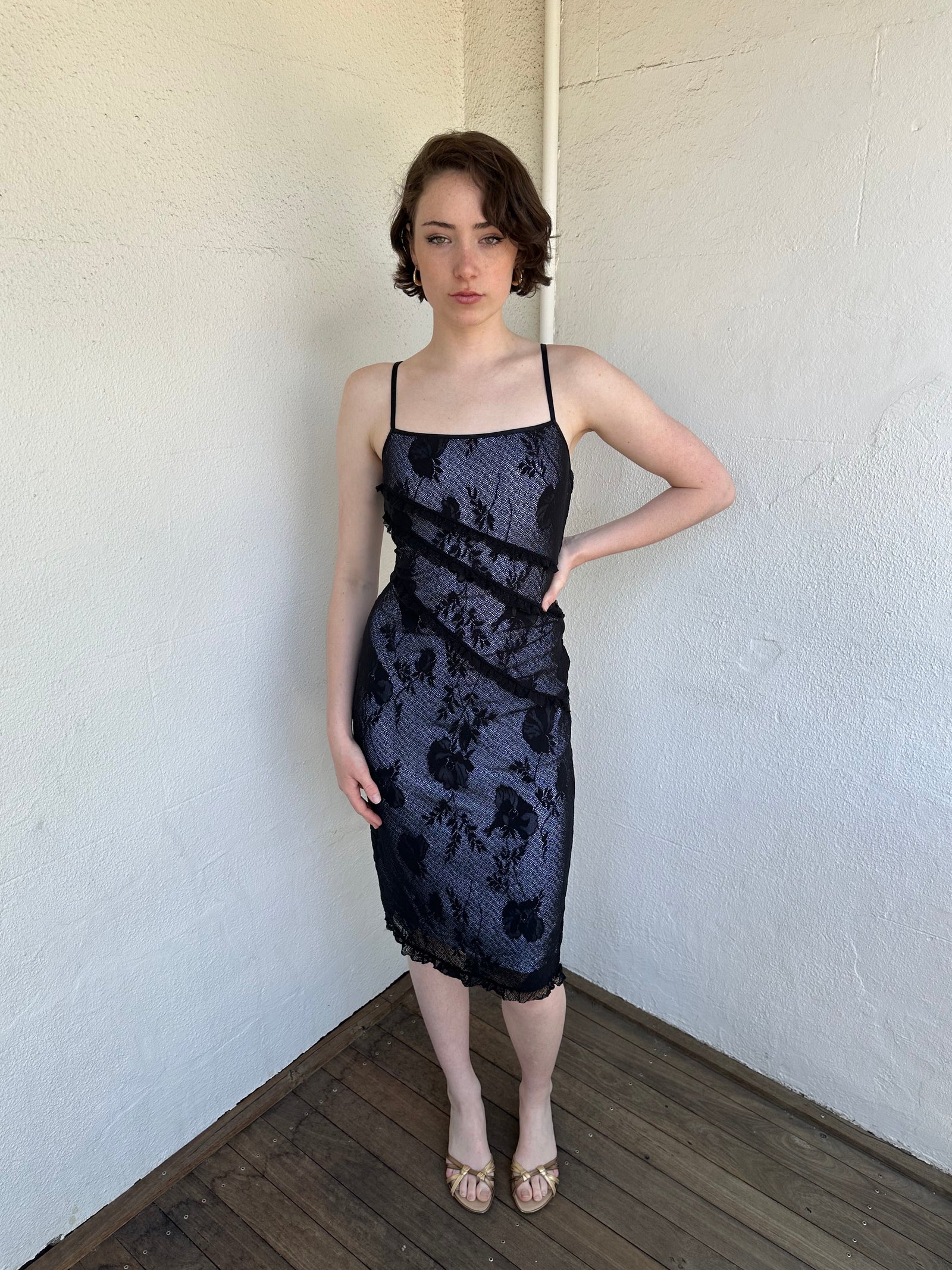 Woman Dressed in Y2K Black floral lace midi dress featuring black lace layered over a white base.