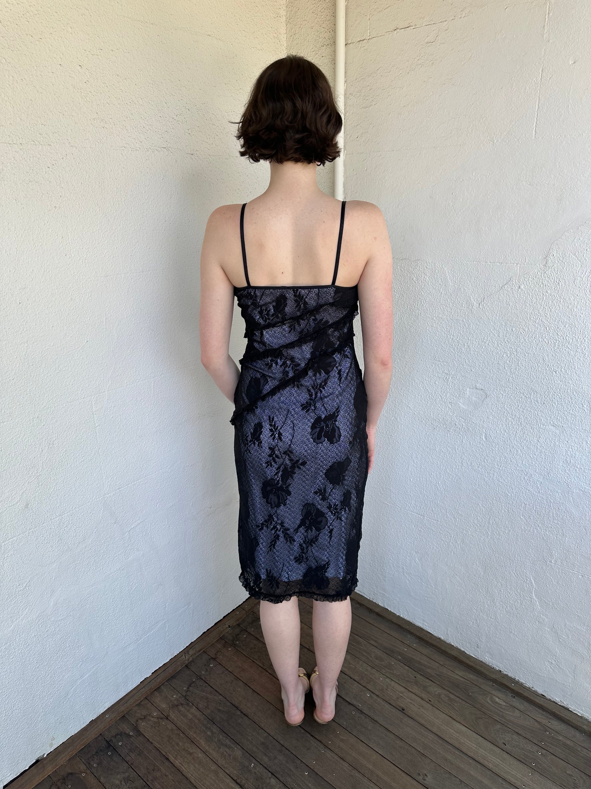 Woman Dressed in Y2K Black floral lace midi dress featuring black lace layered over a white base.