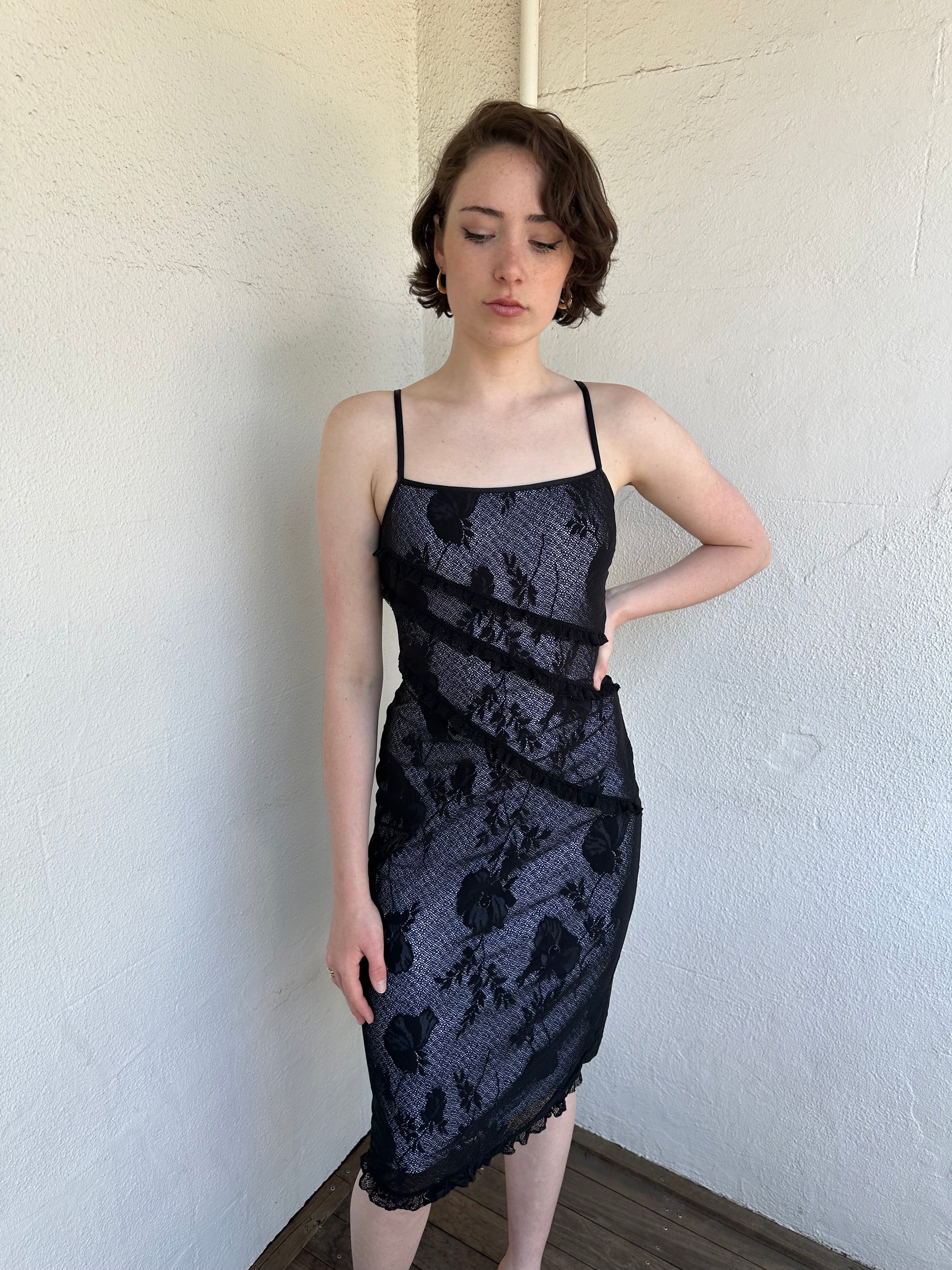 Woman Dressed in Y2K Black floral lace midi dress featuring black lace layered over a white base.