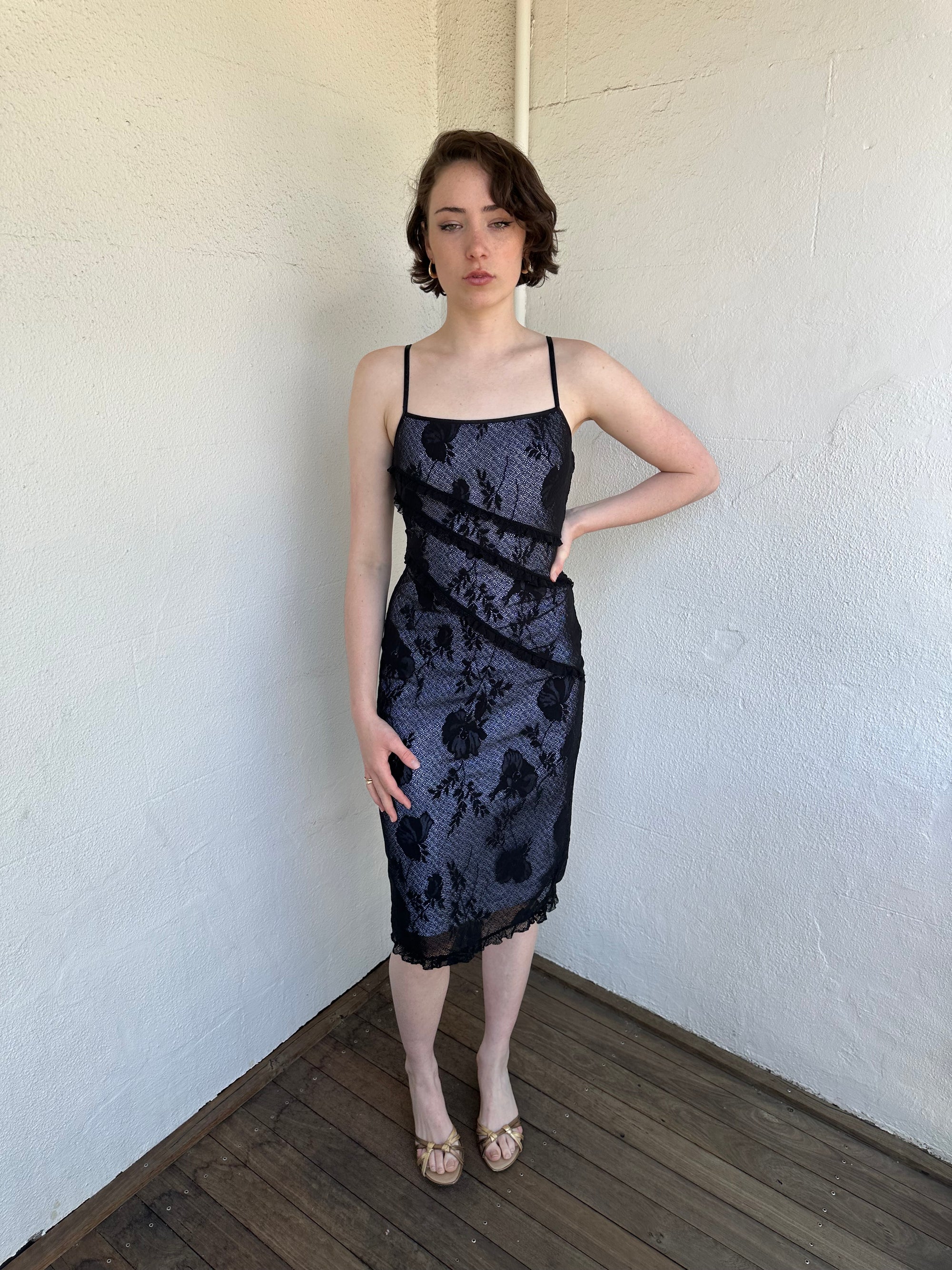 Woman Dressed in Y2K Black floral lace midi dress featuring black lace layered over a white base.