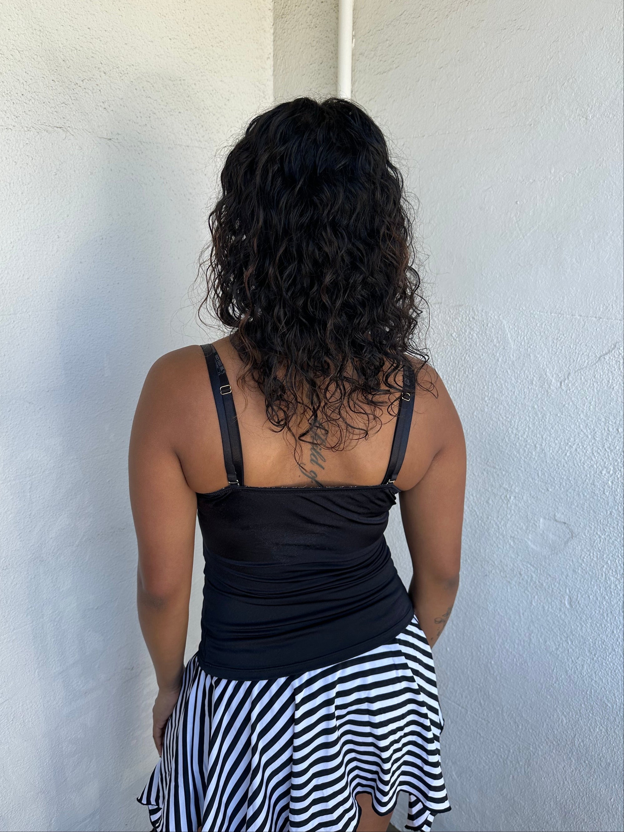 Woman Dressed in Y2K 00s Black lace corset top featuring a stretchy, non-boned fit with a lace front panel layered over a silver satin base.