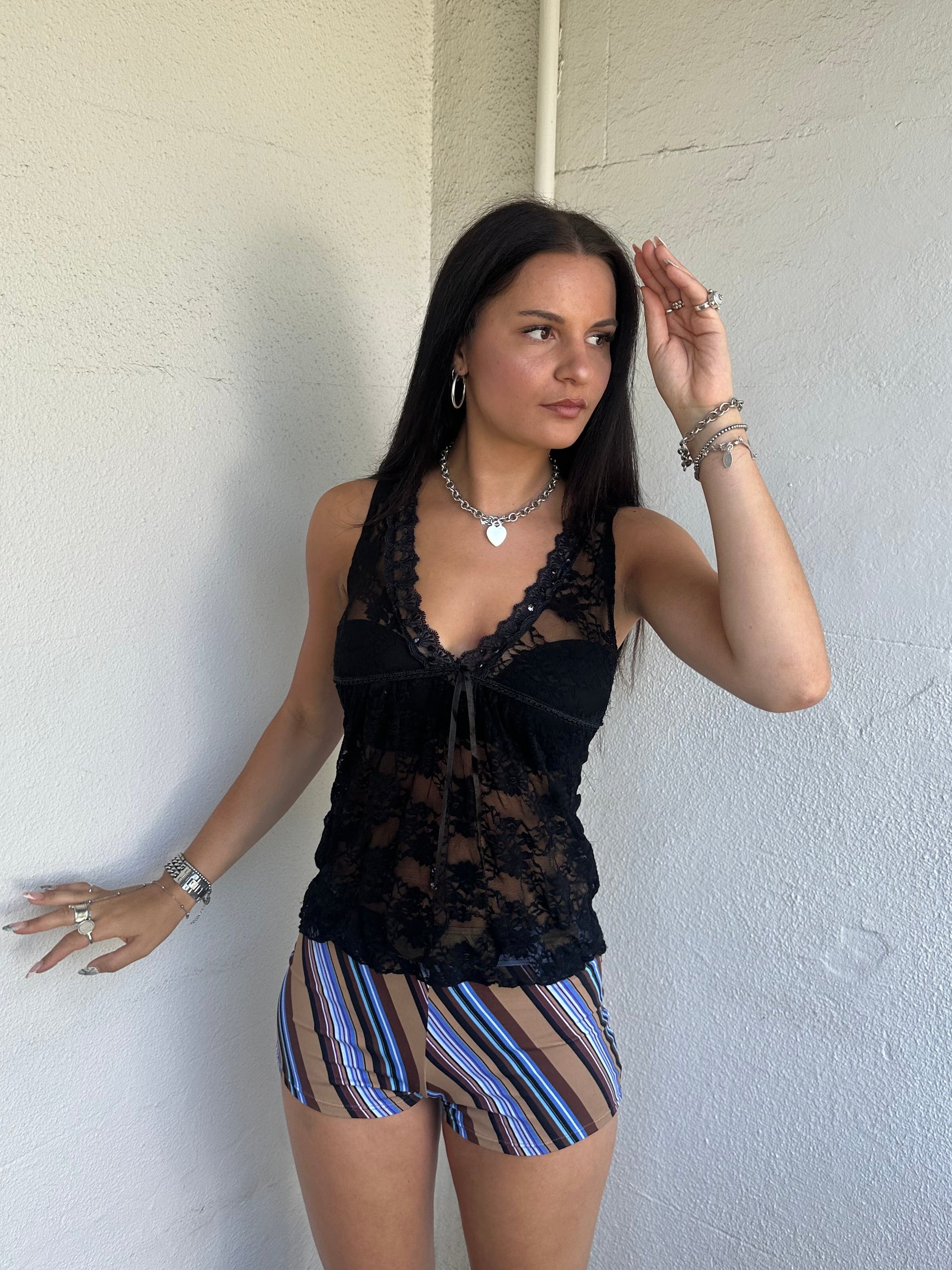 Woman Dressed in Y2K 00s Black lace ribbon detail tank top featuring a completely sheer fabric with a V-neckline and delicate ribbon bow detail at the bust.