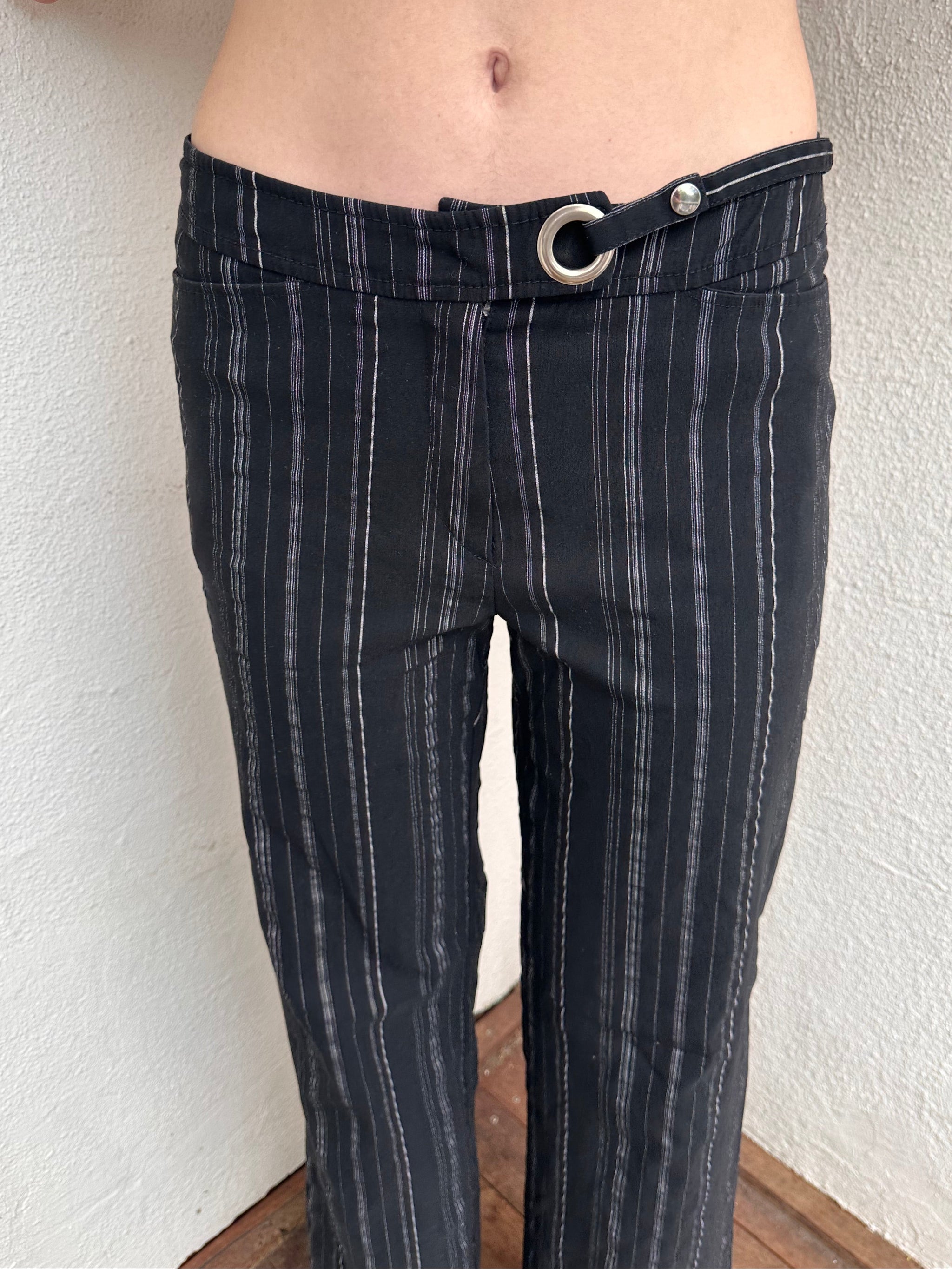 Women wearing a 00s Y2K Black and white pinstripe suit pants with a built-in grommet-look belt and straight-leg cut. 