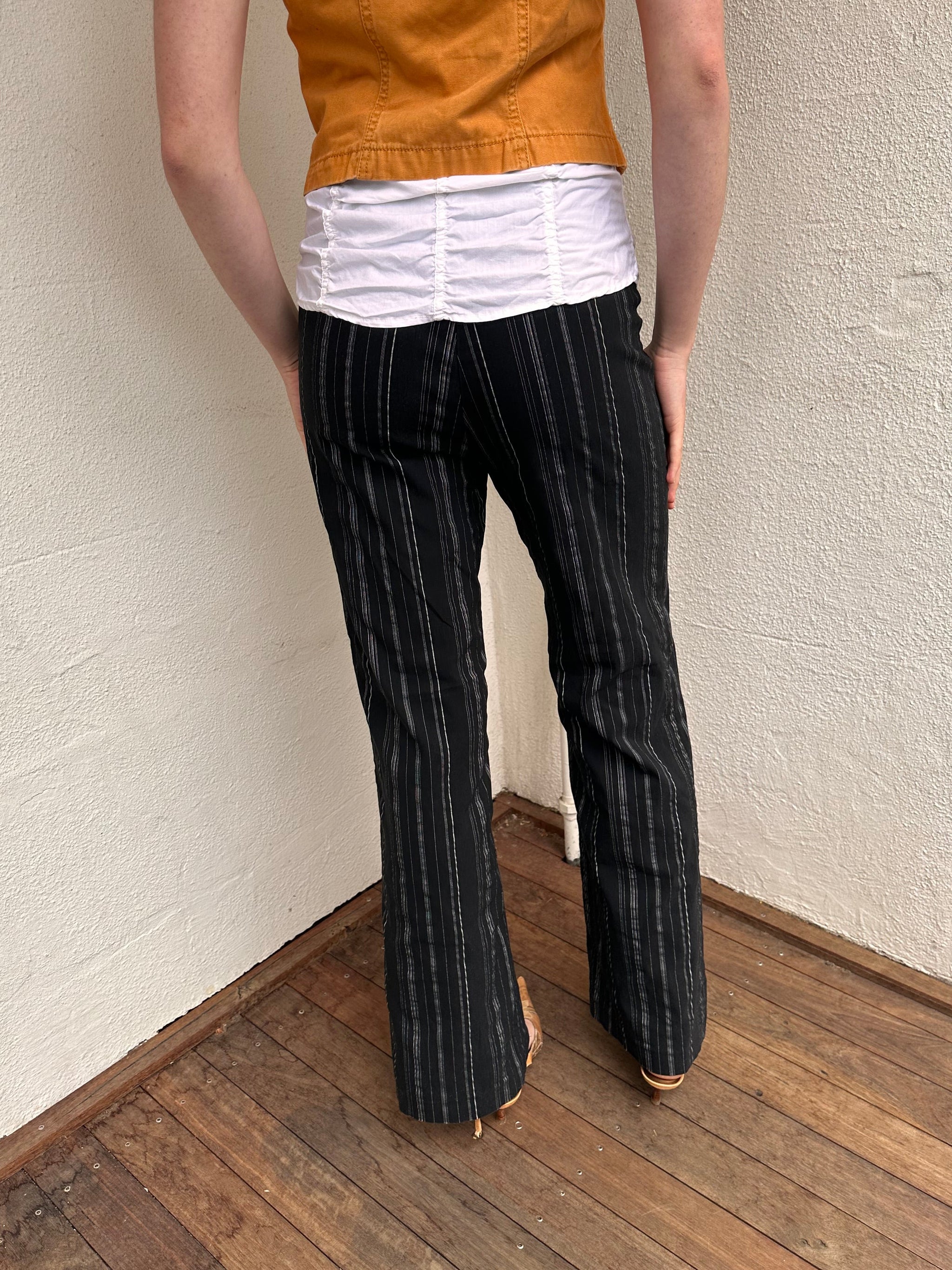 Women wearing a 00s Y2K Black and white pinstripe suit pants with a built-in grommet-look belt and straight-leg cut. 