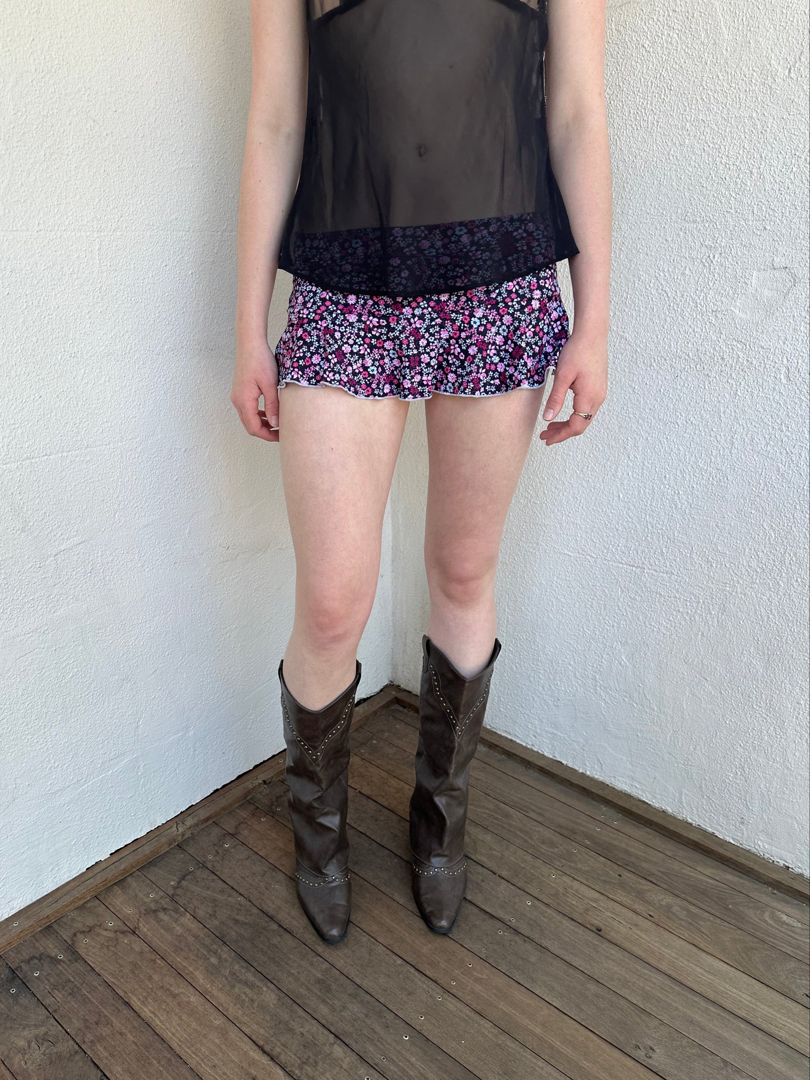 Woman Dressed in Y2K Black and pink floral mini skirt featuring a black base with pink floral detailing throughout. 