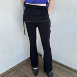 Woman Dressed in Y2K Black rhinestone detail skirt pants featuring a mini skirt attached over flared pants. 