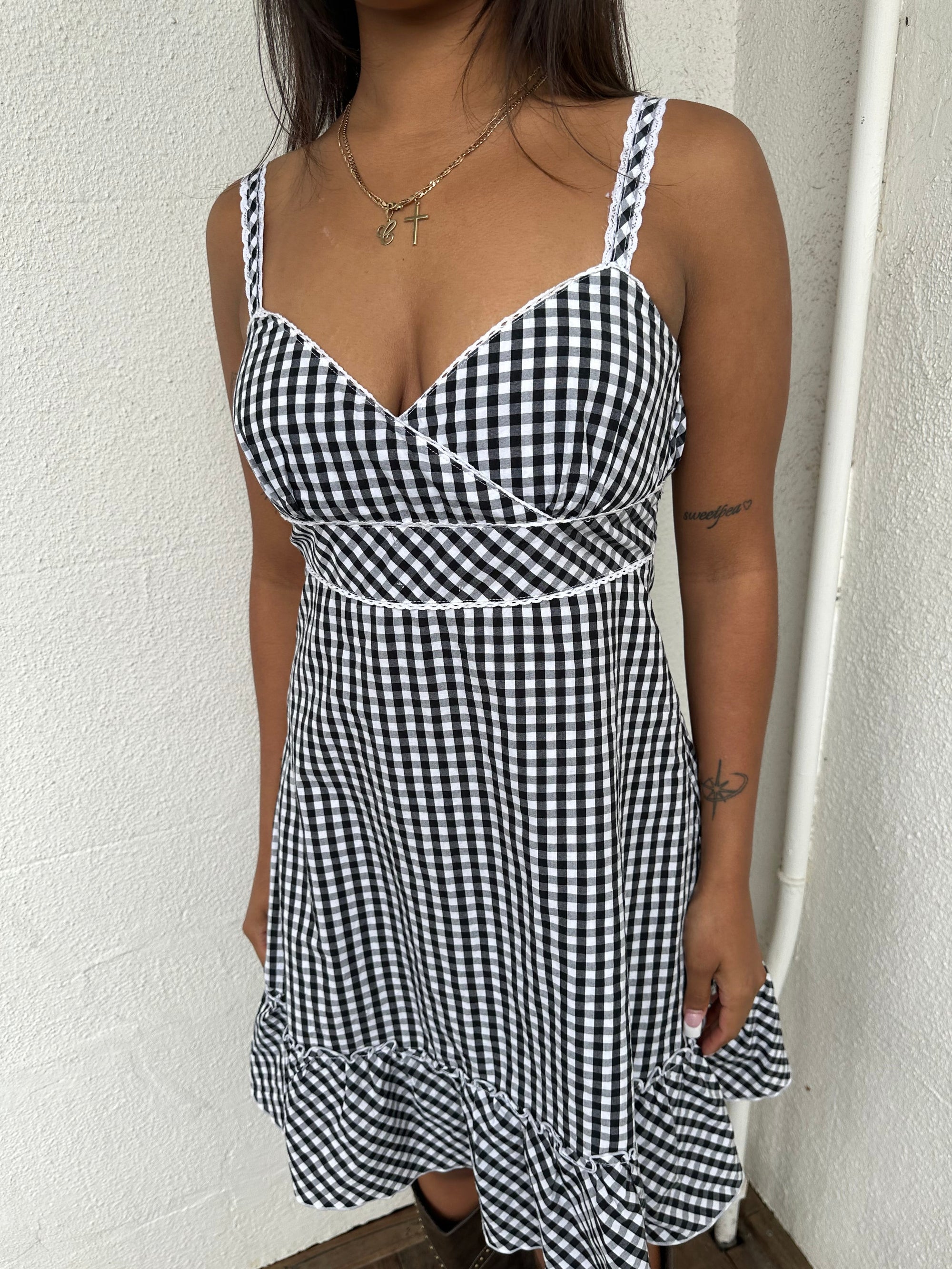 Woman Dressed in Y2K 00s Black and white checkered dress with a fitted bodice, flared skirt, and ruffle hem