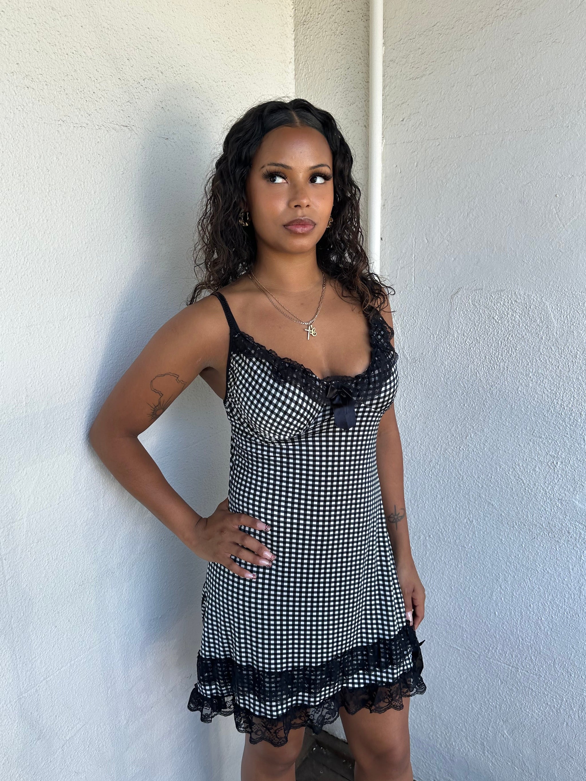 Woman Dressed in Y2K 00s Black and white checkered mini dress with a fitted bodice and flattering mini-length silhouette.