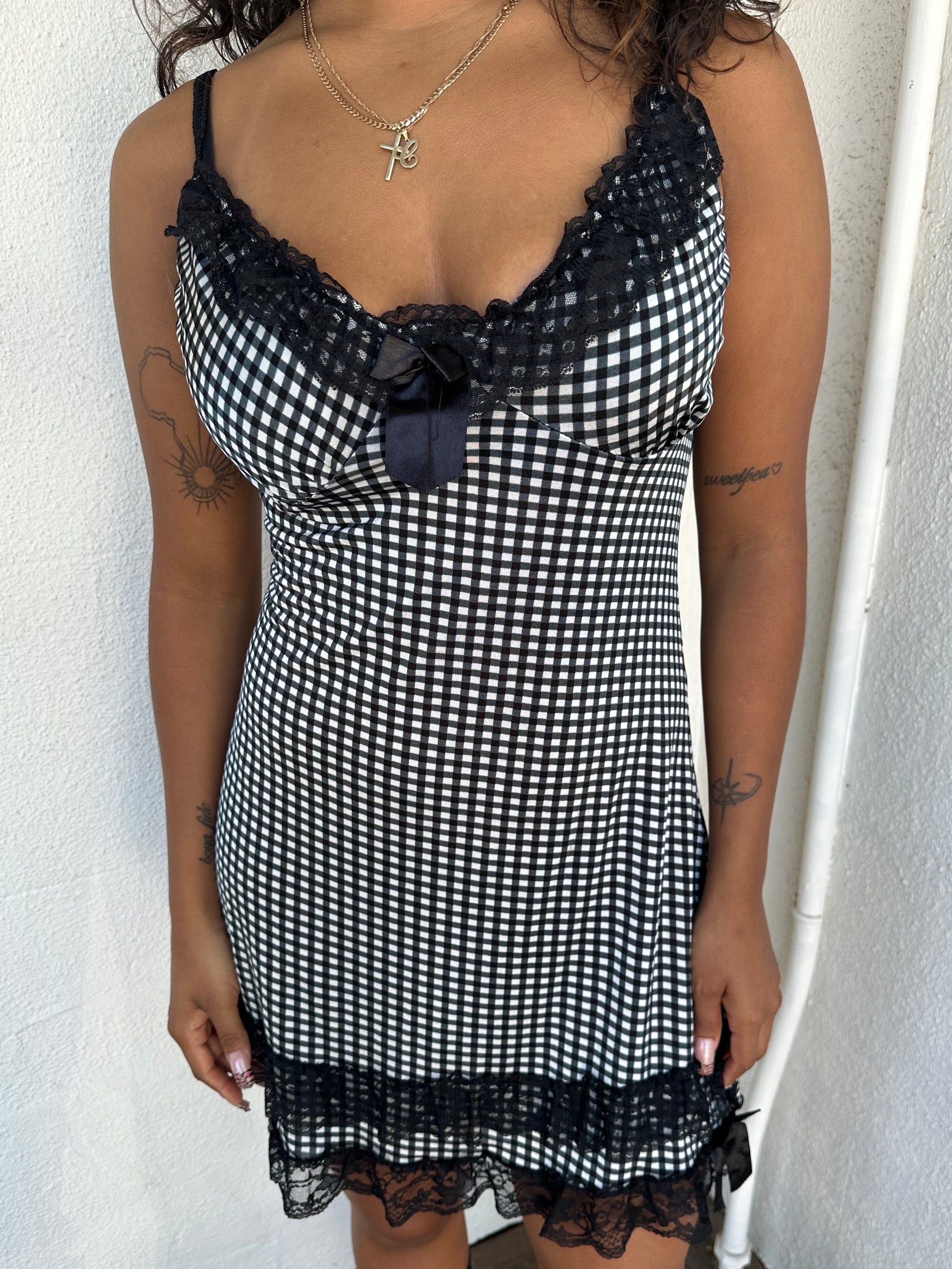 Woman Dressed in Y2K 00s Black and white checkered mini dress with a fitted bodice and flattering mini-length silhouette.