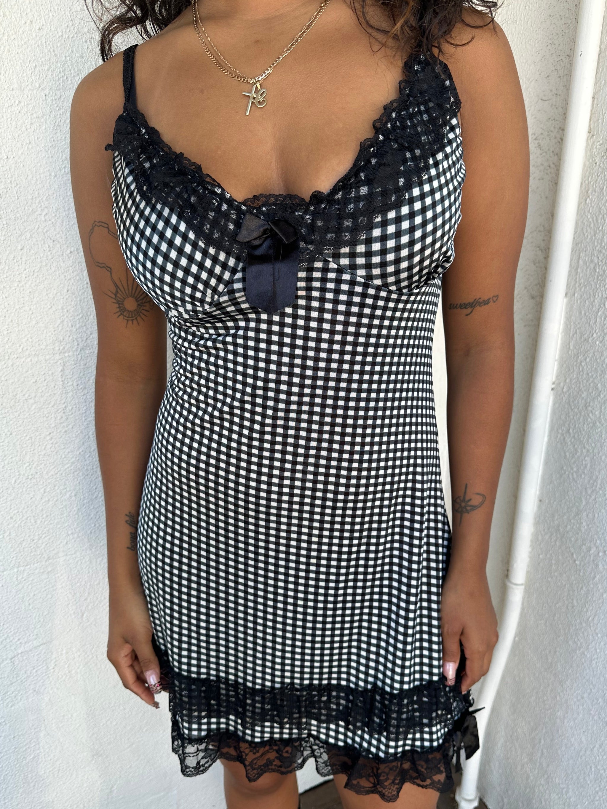Woman Dressed in Y2K 00s Black and white checkered mini dress with a fitted bodice and flattering mini-length silhouette.