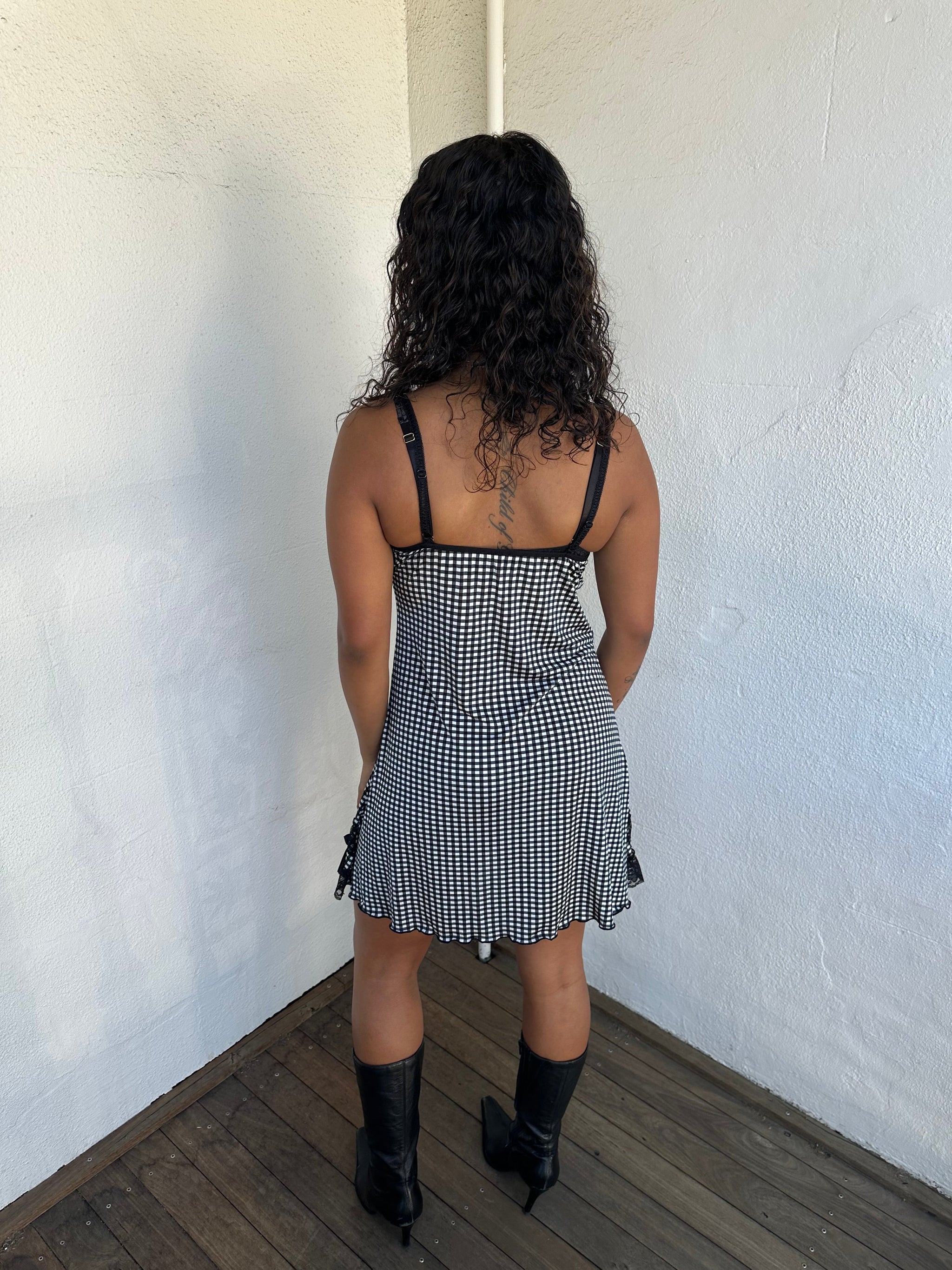 Woman Dressed in Y2K 00s Black and white checkered mini dress with a fitted bodice and flattering mini-length silhouette.