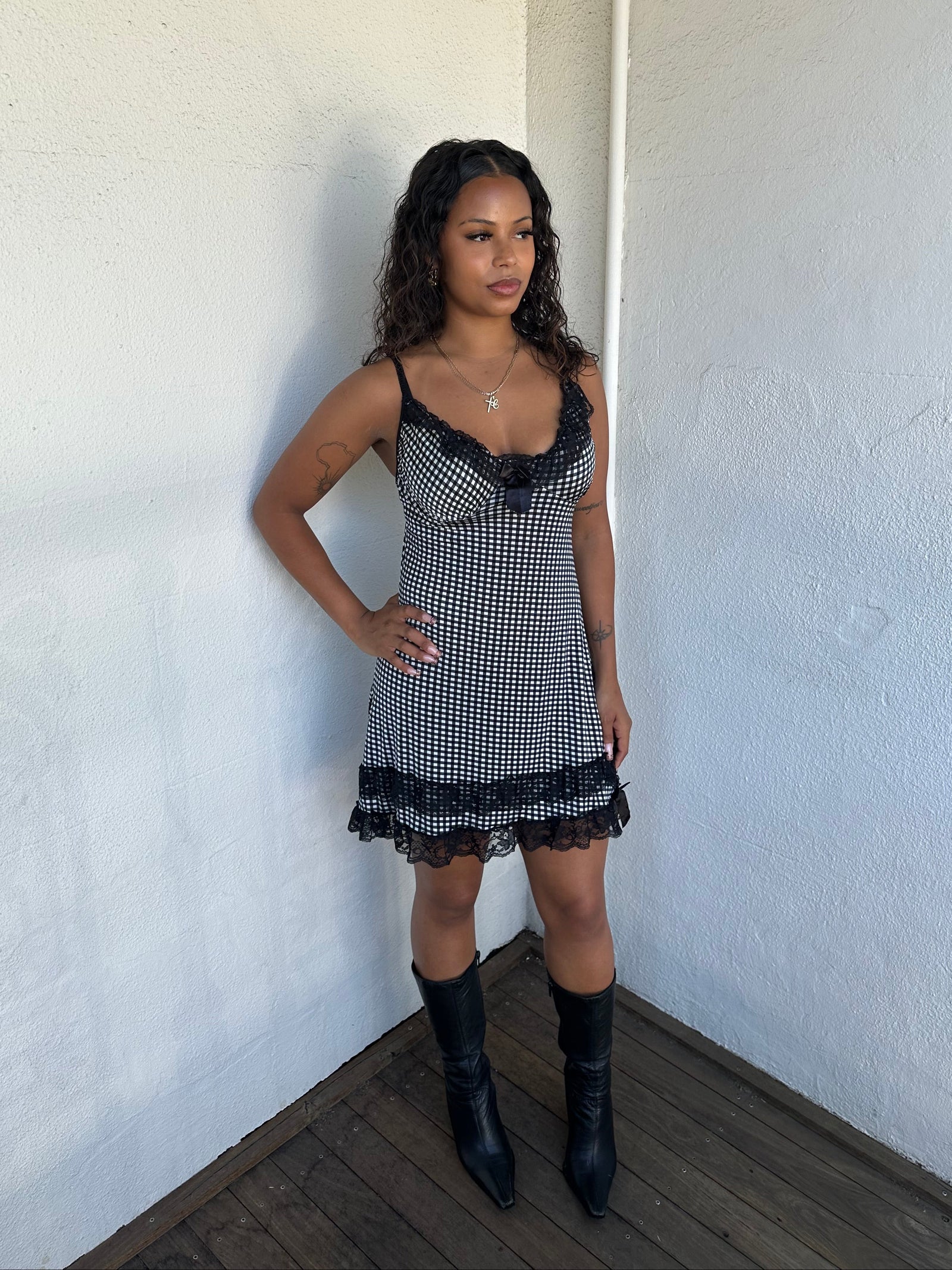 Woman Dressed in Y2K 00s Black and white checkered mini dress with a fitted bodice and flattering mini-length silhouette.